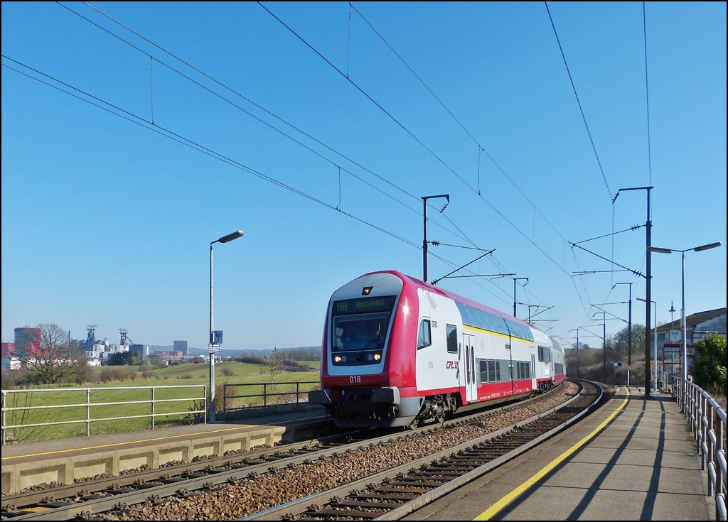 . Die RB (Regionalbunn) 6814 Luxembourg - Rodange fhrt am 04.03.2013 pnktlich in die Haltestelle Belval-Rdange ein, vor der Kulisse der Industriebrache Esch-Belval.

Die Industriebrache Esch-Belval erstreckt sich auf einer Flche von 122,7 ha westlich der Stadt Esch-sur-Alzette bis zur der franzsischen Grenze. Dort befand sich fast ein Jahrhundert lang das integrierte Schmelz/Stahl- und Walzwerk Arbed Esch-Belval.
 
Heute stehen dort noch, als berbleibsel der frhreren industriellen Aktivitt, die beiden Hochfen A (rechts) und B (links), sowie die Geblsehalle und die Mllerei. 

Die beiden Hochfen A und B wurden zwischen 1965 und 1979 gebaut, sie haben eine Hhe von 82, respektiv 90 Meter. Der Hochofen B war der letzte, der in Luxemburg aktiv war, sein Betrieb wurde 1997 gestoppt.

Seit 2001 stehen die beiden letzten Hochfen auf der Liste der klassierten Monumente in Luxemburg. 27 Millionen Euro wurden zur Verfgung gestellt, um die Hochfen zu entrosten und zu sanieren. Der Hochofen A soll komplett saniert werden, whrend der Hochofen B nur als Silhouette stehen bleiben soll. (Jeanny)


