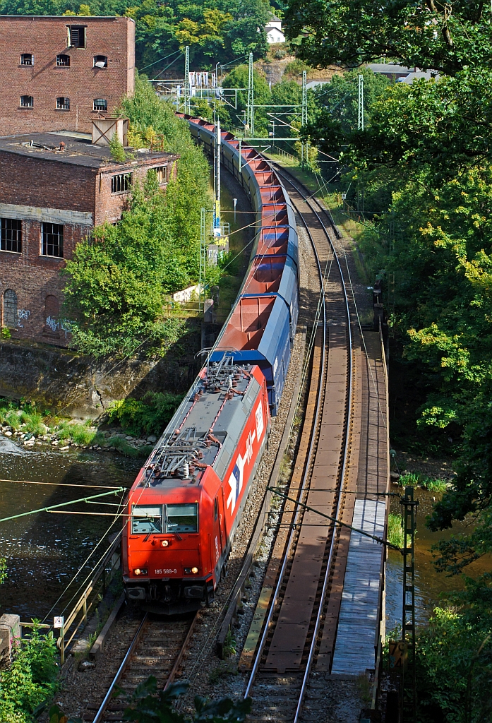 185 589-9 der HGK (Hfen und Gterverkehr Kln AG) mit einem sehr langen Ganzzug von leeren VTG Selbstentladewagen (Falns) und am Schluss waren dann noch 2 Class 66 (JT42CWR) Lokomotiven der Ascendos Rail (vormals CBRail), hier am 19.08.2012 auf der Siegbrcke kurz vor dem Mhlburg-Tunnel in Scheuerfeld/Sieg. Der Gterzug fhrt in Richtung Kln.