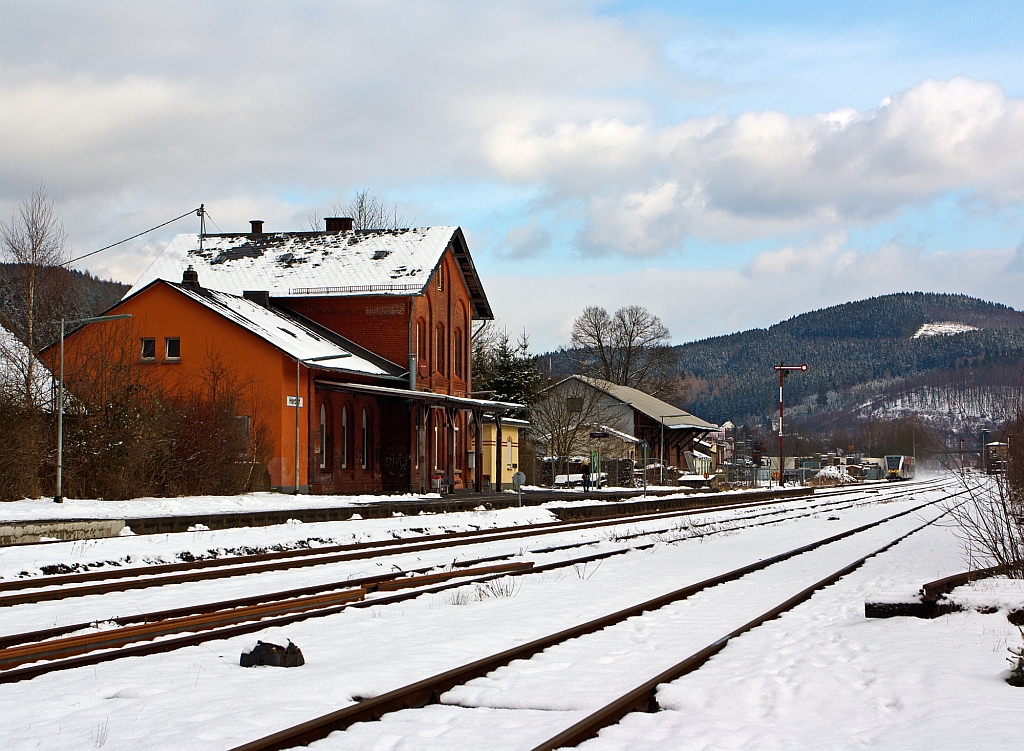 Blick auf den Bahnhof Herdorf am 09.02.2013. 
Vorne das ehem. Empfangsgebude, rechts davon der ehem. Gterschuppen und ganz hinten im Bild rechts das Stellwerk Herdorf Ost (Ho). 
Ein Stadler GTW 2/6 der Hellertalbahn kommt von Neunkirchen und fhrt gerade in den Bahnhof ein. 
Den GTW wollte ich hier eigentlich vor dem Bahnhof ablichten, aber aufgrund der nchtlichen neuen Farbgebung (Schmierereien) musste ich darauf verzichten
