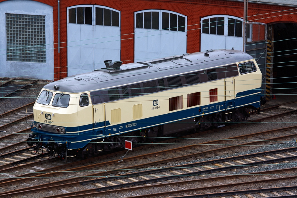 Die 218 128-7 steht am 21.07.2012 vor dem Siegener Lokschuppen, Blick vom Parkdeck der City Galerie.
Die Lok wurde 1971/72 bei Krupp unter der Fabriknummer 5149 gebaut, die Ausmusterung erfolgte am 27.05.2010.
Sie hat einen MTU-Motor vom Typ 12 V 956 TB 10  mit 1839 kW/ 2500 PS Leistung, die Hchstgeschwindigkeit betrgt 140 km/h.