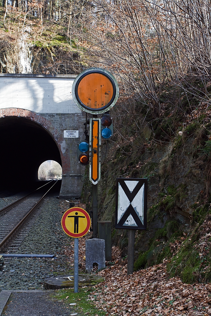 (Form-) Vorsignal: Dieses zeigt Vr 0 - Halt erwarten! (Eine gelbe Scheibe mit weiem Rand, ein vorhandender gelber Pfeil zeigt nach unten, fr Nachts zwei gelbe Lichter, nach rechts oben steigend.
Rechts unten  die Vorsignaltafel (Ne 2 ). Die Vorsignaltafel zeigt dem Lokfhrer, da das Signal, vor dem sie steht, Vorsignalfunktion hat, d.h., den Begriff eines nachfolgenden Hauptsignales vorankndigt. 
Aufnahme hinter den Herdorfer Tunnel am 04.02.2012