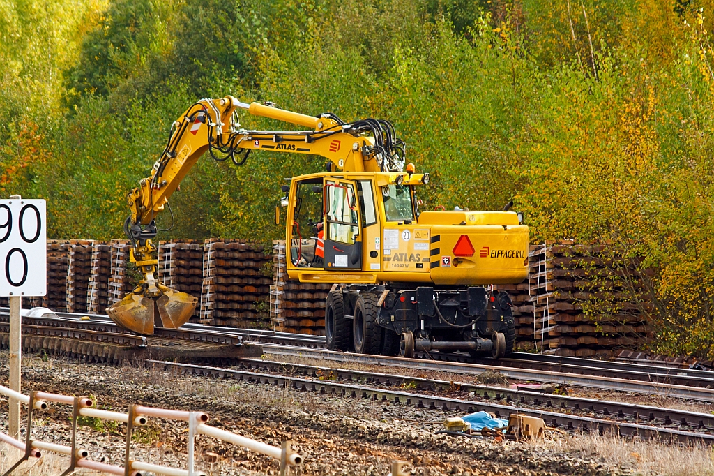 
Gleisbaustelle Bf. Herdorf am 13.10.2012 (Erneuerung Gleis 2) - Arbeiter lsen die Schienenbefestigungen, zuvor wurden die Schienen durchgebrannt und das komplette Gleis in Segmenten auf Gleis 3 abgelegt. Mit einem Zweiwegebagger werden Schwellen beiseite gelegt.