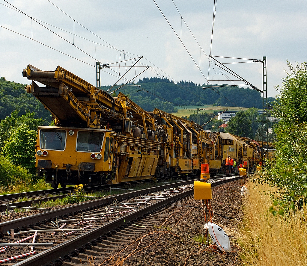 
Plasser & Theurer Planumsverbesserungsmaschine RPMW 2002–2 der GBM Wiebe Gleisbaumaschinen GmbH, Schweres Nebenfahrzeug Nr. 99 80 9415 002–1 am 13.07.2013 bei Katzenfurt (Lahn-Dill-Kreis) an der KBS 445 (Dillstrecke). Die Maschine steht, da die MSF-Wagen mit Abraum voll waren und entladen werden mssen.

Der groe Unterschied zwischen Planumsverbesserungsmaschine und Bettungsreinigungsmaschinen besteht darin, dass Planumsverbesserungsmaschine nicht nur den Schotter ausheben und recyceln kann sondern auch einen Teil Planums (Unterbau) ausheben (bis 1.200 mm unter SO). Zudem kann die RPM vor der Neuschotterung (Recycling- mit Neumaterial) auch eine Planumsschutzschicht (PSS-Material) einbringen.

Die RPM 2002 – 2 ist die hat ein Gewicht von 560 t und hat eine Lnge ber Puffer von 140 m. Die Motorengesamtleistung betrgt 2.860 PS / 2.100 kW die aber weniger der Fortbewegung dienen, sonder zur Erzeugung der hydraulischen und elektrischen Energie.

Der Neuschottern wird durch die Stopfeinrichtung 09-32 Stopfsatellit das Gleisbett verdichtet und ist danach wieder mit 70 km/h befahrbar.
