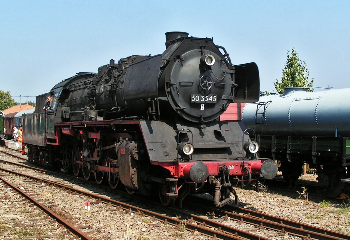 . Am 08.08.2004 setzt die Dampflok 50 3545 im Bahnhof von Losheim am See um, amlsslich des Dampflok- und Bahnpostfestivals 2004 organisiert vom Museums-Eisenbahn-Club Losheim. (Hans)

Die Geschichte der Gterzuglokomotive 50 3545 der DBK Historische Bahn e.V.:

Die 50 3545 wurde als erste Lokomotive der Baureihe 50 aus dem Baulos der Maschinenfabrik Esslingen 1941 unter der Betriebsnummer 50 1385 abgeliefert. Bei Kriegsende blieb die zur Direktion Hannover zhlenden Lok in Sachsen-Anhalt stehen und anschlieend in den Betriebslokpark in der DDR eingereiht. Sie ist ein von vier Lokomotiven aus den Hallen der Maschinenfabrik Esslingen, die in der DDR einer umfassenden Modernisierung unterzogen wurde. Aufflligstes Merkmal ist dabei der neue Hochleitungskessel mit seinem Mischvorwrmer auf der Rauchkammer. Von diesen vier Loks blieb neben der 50 3545, wie sie nun genannt wurde, nur noch eine erhalten.

Ab 1970 erhielt die Lok die computergerechte Nummer 50 3545-6. Als eine der wenigen Lokomotiven zhlte die 50 3545 auch nach der Vereinigung der Deutschen Reichsbahn  der DDR und der Deutschen Bundebahn zur Deutschen Bahn AG zum Betriebsbestand. Die in Wismar beheimatete Lok diente unter der neuen DB-AG-Nummer 050 545-3 als Ausbildungslokomotive. Am 6. Dezember 1995 schied sie – zusammen mit der 52 8134 des Bw Berlin-Pankow (Z-Stellung am, 4.12.1994) - als letzte Staatsbahn-Dampflokomotive aus dem aktiven Dienst.

Die Lok wurde von der DBK Historischen Bahn Verein im Sommer 1996 ab Standort Meiningen erworben und nach Abschluss der Hauptuntersuchung im Dampflokwerk Meiningen ab April 1997 eingesetzt. Immer wiederkehrende Lagerschden zwangen den Verein, die Lok im Herbst 1999 nach einem erneuten Lagerschaden, vorerst abzustellen. Nach umfangreichen Fahrwerksreparaturen wurde die Lok inkl. einer Kesselhauptuntersuchung im Mai 2002 wieder in Betrieb genommen. Danach stand die Lok dem Verein jahrelang zuverlssig zur Verfgung und kam bei ihren vielen Sonderfahrten um Einsatz. Am 4. Dezember 2005 erlitt die Lok auf Grund eines Wasserschlages leider einen schweren Triebwerkschaden und ist seither in Crailsheim konserviert abgestellt. Ihre Reparatur bzw. Wiederinbetriebnahme ist derzeit nicht geplant. 

Die technischen Daten der 50 3545:

Baujahr: 1942
Leistung: 1650 PS
Hchstgeschwindigkeit: 80 km/h
Wasser: 26 m
Kohle: 8 Tonnen
HU-Abnahme: 11.05.2005
Fristablauf: Abgestellt wegen Triebwerkschaden
Hersteller: Maschinenfabrik Esslingen
