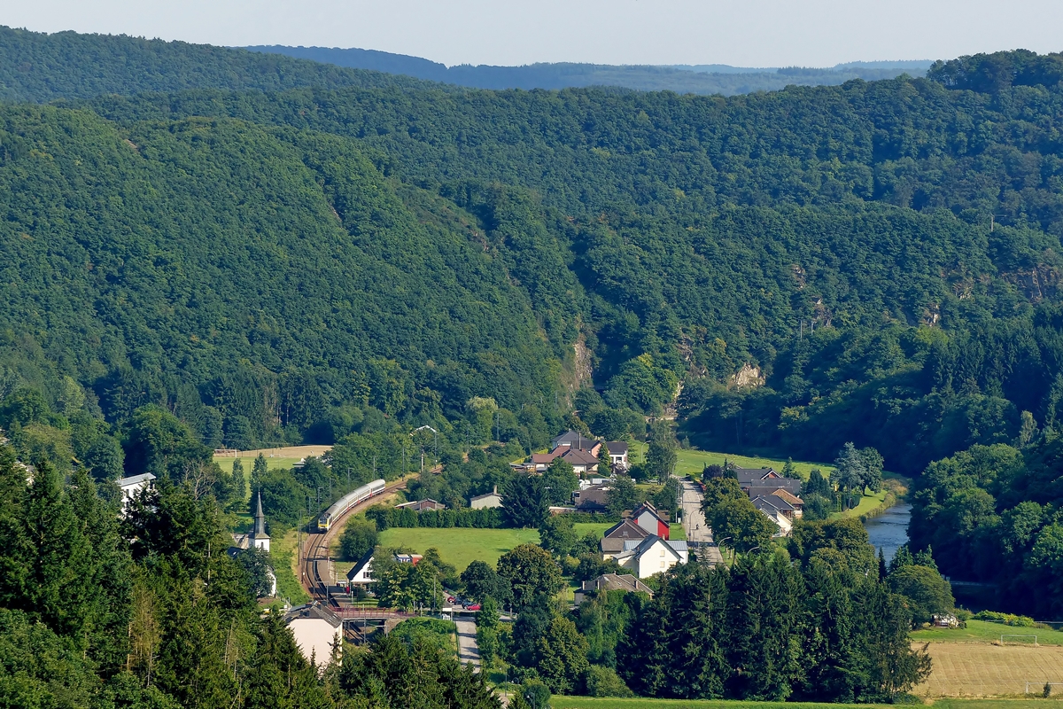 . Grnes Sauertal - Im Sommer dominiert die Farbe Grn in Michelau, wenn der IR 118 Luxembourg – Liers das Sauertal durchfhrt. Er hat am 01.08.2014 den Tunnel Michelau verlassen und nhert sich der Straenbrcke, von welcher aus man eine schne Aussicht auf die Burg Bourscheid hat. Logischerweise bietet die Strae etwas unterhalb der Burg ihrerseits einen herrlichen Ausblick auf die Nordstrecke in Michelau. (Jeanny)