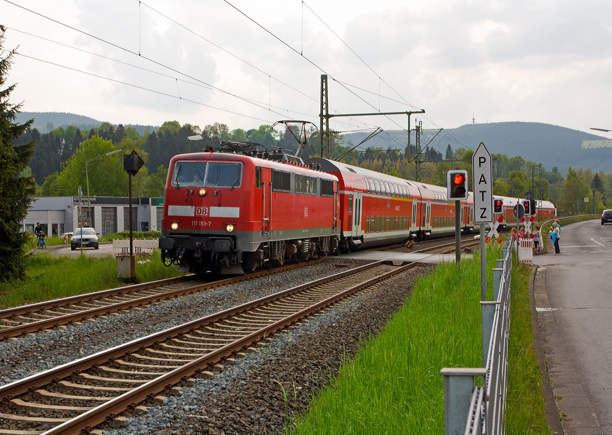 
111 151-7 der DB Regio NRW fährt am 01.05.2014 mit dem RE 9 - Rhein-Sieg-Express (Aachen-Köln-Siegen) in Richtung Siegen, hier beim Bahnübergang in Mudersbach (Bü km 114,7).  

Einen lieben Gruß an den freundlichen Lokführer retour. 

Der Bahnübergang ist eigentlich für LKW über 7,5 t zul. Gesamtgewicht tabu, doch haben immer einige Lkw-Fahrer ihn verbotswidrig überquert, obwohl er zu eng für die langen 40-Tonner ist.  
So hatte sich zuletzt am 26. November 2013, ein Sattelzug sich am Bahnübergang festgefahren und der Regionalexpress RE 9 war in ihn gefahren, zum Glück ohne größere Katastrophe. Drei Personen wurden dabei leicht verletzt, neben dem Zugführer und einem Fahrgast auch ein Passant, der sich in der Nähe aufhielt. 

Nun werden auf der Straße vor und hinter den Bahnübergang eine Konstruktion zur Höhenbegrenzung (2,80 m) aufgestellt, die Fundamente sind schon letzte Woche gemacht worden, und am 19. Mai soll die Montage der eigentlichen Begrenzung erfolgen.

Die 111er wurde 1981 bei Krauss-Maffei AG in München unter der fabriknummer 19863 gebaut. 
Sie hat die NVR-Nummer 91 80 6111 151-7 D-DB und die EBA-Nummer EBA 01G02A 151.