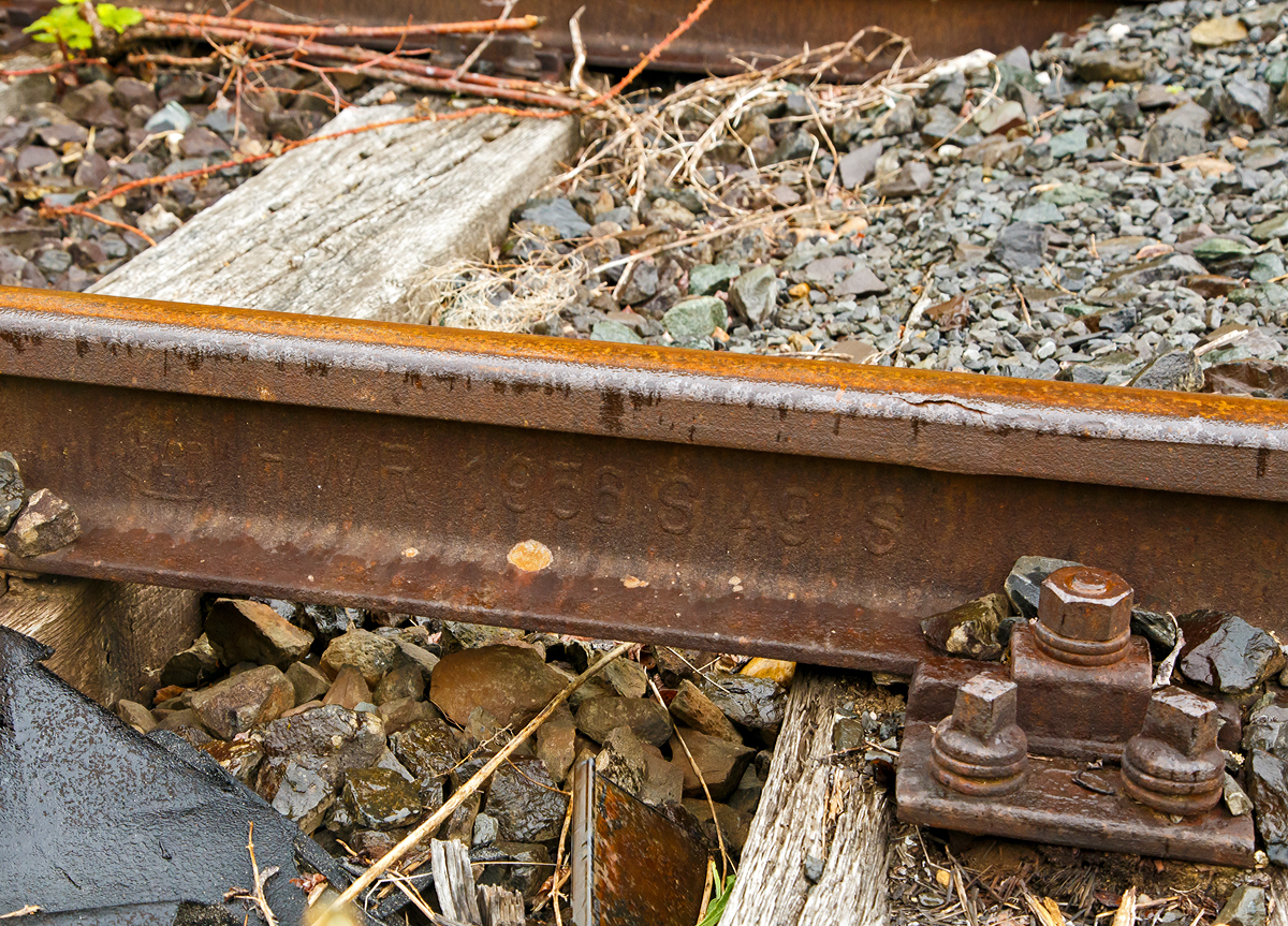 
Altes Schienen-Walzzeichen, fotografiert am 24.05.2020 im dem stillgelten Bereich des Rbf. Betzdorf (Sieg).

Anhand des Walzzeichens sieht man:
Den Hersteller:
HWR = Hütten- und Bergwerke Rheinhausen AG, es war eine Gesellschaft innerhalb des kruppschen Firmenimperiums. Am 3. Dezember 1982 gab die Krupp Stahl AG die Schließung ihres Walzwerks in Duisburg-Rheinhausen bekannt. 1987 erhielt Rheinhausen durch den Widerstand gegen die Schließung des damals vorhandenen Stahlwerks große Medienpräsenz.

Das Herstellungsjahr: 1958

Das Schienenprofil (und das ungefähre Metergewicht): 
S 49 Schiene 49,43 kg/m, Höhe 149mm, Fußbreite 125 mm, Schienenkopfbreite 67 mm, Stegstärke 14 mm, Wiederstandsmoment (Wx) 240 cm³

Das Stahl-Herstellungsverfahren: S = Siemens-Martin-Stahl
Ein Kennzeichen für die genaue Stahlqualität gibt es nach den alten Walzzeichen nicht.
