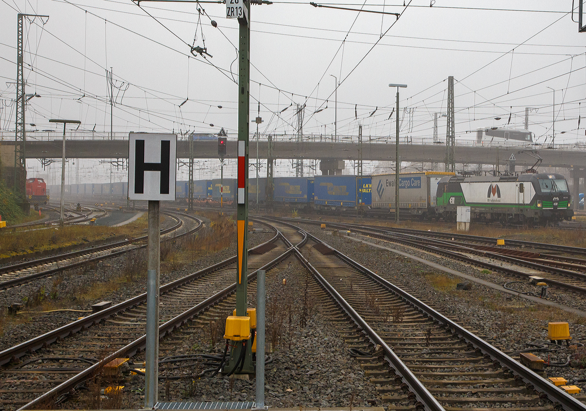 Aus dem Nebel kommend....
Die an die MMV-Rail Austria Ges.m.b.H.( Wiener Neudorf)  vermietete Siemens Vectron 193 212 (91 80 6193 212-8 D-ELOC) der European Locomotive Leasing, fährt am 12.11.2021 mit einem KLV-Zug durch den Bahnhof Gießen in nördlicher Richtung (Marburg). 

Die Siemens Vectron AC  wurde 2014 von Siemens Mobilitiy in München-Allach unter der Fabriknummer  21912 gebaut. Diese Vectron Lokomotive ist als AC– Lokomotive (Wechselstrom-Variante) mit 6.400 kW konzipiert und zugelassen für Deutschland, Österreich, Ungarn und Rumänien (D/A/H/RO) , sie hat eine Höchstgeschwindigkeit von 160 km/h.
