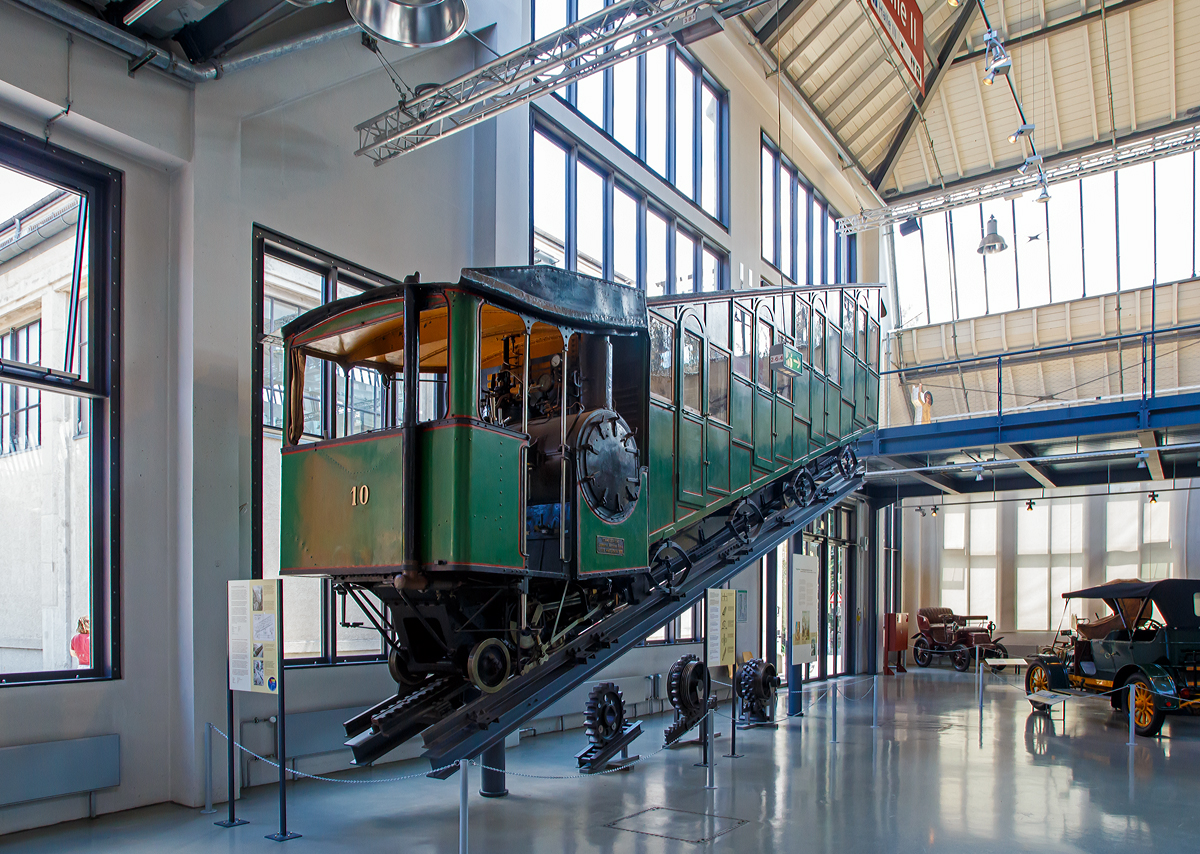 
Bhm 1/2 Zahnrad-Dampftriebwagen Nr.10 der Pilatus Bahn ausgestellt im Verkehrszentrum des Deutschen Museums in München (Theresienhöhe), hier am 16.06.2018. Leihgabe der Pilatus Bahnen.

Der Dampftriebwagen wurde 1900 von der SLM unter der Fabriknummer 1309 gebaut und an die Pilatus Bahn geliefert.

Mit Seilbahnen und Zahnradbahnen eroberten Touristen und Ausflügler am Ende des 19. Jahrhunderts die Einsamkeit der Berge. Als erster Schweizer Berg erhielt der sanfte Rigi 1875 die erste Bergbahn Europas. Nach dessen erfolgreicher Eroberung galt es dem schroffen und sagenumwobenen Pilatus am Vierwaldstätter See mit einer Bergbahn zu Leibe zu rücken. Eine besondere technische Herausforderung stellte dabei die starke Neigung der bevorzugten Trasse dar.

Eduard Locher entwickelte dafür 1888 ein Zahnstangensystem. Dank der liegenden Anordnung seiner Fischgrätenzahnstange und dem horizontalen Zahneingriff mit dem liegenden Zahnradpaar war eine Steigung von 48 % realisierbar.

Am 4. Juni 1889 dampfte der erste fahrplanmäßige Zug zum Pilatus. Er brauchte für die 4,3 Kilometer lange Strecke 70 bis 80 Minuten. Bereits 1895 reisten 40.000 Besucher per Zahnradbahn auf den Pilatus. Neun Dampftriebwagen waren dafür im Einsatz. Später kamen noch die Triebwagen 10 (1900) und 11 (1909) hinzu..

Die Triebwagen versahen größtenteils bis zur Umstellung auf elektrischen Betrieb im Jahre 1937 ihre Dienste. Mit den elektrischen Triebwagen konnte man mit weniger Personal in kürzerer Zeit mehr Gäste befördern. Bis auf die Dampftriebwagen 9 und 10 wurden die restlichen Fahrzeuge noch im selben Jahr verschrottet. Wagen 9 blieb bis 1981 als Reserve bei der Pilatusbahn und ist seitdem im Verkehrshaus der Schweiz in Luzern ausgestellt, Wagen 10 ist eine Dauerleihgabe des Verkehrshauses an das Deutsche Museum in München.

Heute fahren jährlich über 250.000 Besucher mit der steilsten Zahnradbahn der Welt auf den Pilatus, um von hier einen Blick auf die Schweizer Alpenwelt zu werfen.

TECHNISCHE DATEN:
Spurweite: 	800 mm
Achsformel:  2z
Länge über Puffer: 10.300 mm
Achsabstand der Laufräder: 7.200 mm
Leergewicht: 7,6 t 
Dienstgewicht:  13,2 t
Kohlevorrat: 500 kg
Wasservorrat: 880 l
Höchstgeschwindigkeit: 3,6 km/h (bergwärts) / 3 km/h (talwärts)
Leistung: 73 PS
Treibzahnraddurchmesser: 	409 mm
Zahnradsystem: 	Locher
Zylinderdurchmesser: 	235 mm
Kolbenhub: 300 mm
Kesselüberdruck: 12 bar
Anzahl der Heizrohre: 	130
Rostfläche: 	0,40 m²
Strahlungsheizfläche: 	2,40 m²
Verdampfungsheizfläche: 	21,0 m²
Steigung max.: 	48 %
Sitzplätze: 	35
