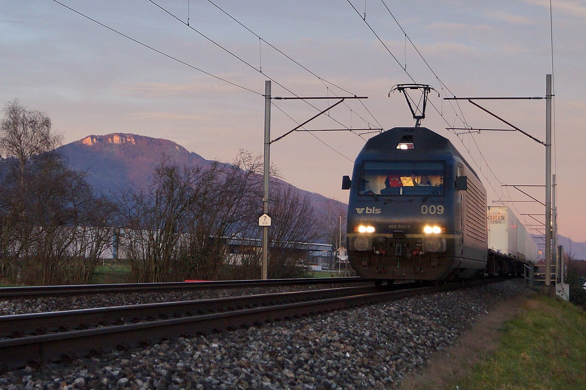 BLS: BLS Re 465 009-9 mit einem Containerzug bei Niederbipp im allerletzten Abendlicht bei Niederbipp. Rechts im Bilde ist die Klus bei Balsthal sichtbar.
Foto: Walter Ruetsch