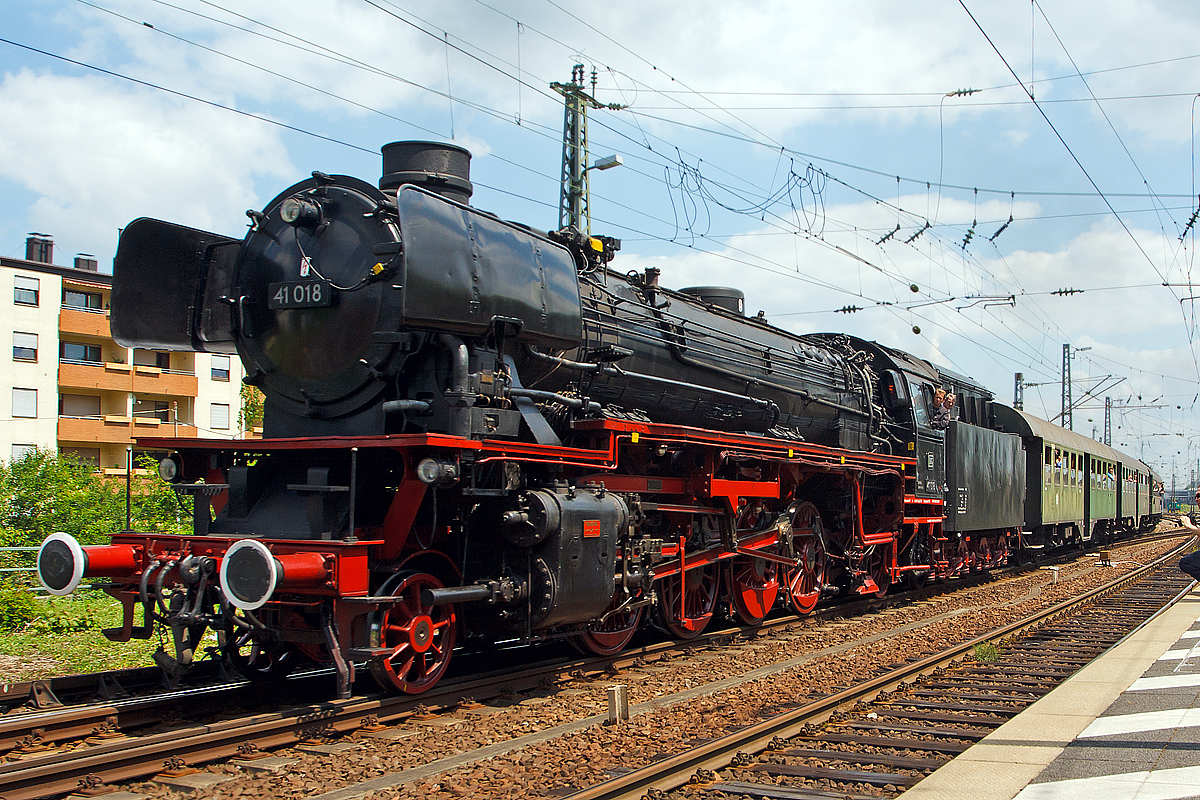 Dampfspektakel 2014 - Die schnelle Güterzug-Einheitsdampflokomotivene 41 018 der Dampflok-Gesellschaft München e.V., ex DB 042 018-2, ex DB 41 018, ex DR 41 018, fährt am 31.05.2014 mit einem planmäßigen Personenzug in den Hauptbahnhof Neustadt a d. Weinstraße ein. Diese Dampfzüge konnten mit einem normalen Nahverkehrsticket genutzt werden.


Zweizylinder-Güterzuglok wurde 1939 von Henschel & Sohn in Kassel unter der Fabriknummer 24320 gebaut. 

Im Januar 1961 rollte die Lok ins Ausbesserungswerk nach Braunschweig, wo sie einen neuen Kessel erhielt. Gleichzeitig wurde die 41 018 von Kohle auf Ölfeuerung umgebaut. Den Kesseltausch machten die zunehmenden Materialermüdung nötig, insgesamt wurden 107 Fahrzeuge der DB mit vollständig geschweißten Verbrennungskammerkesseln versehen, wie sie auch bei der Baureihe 03.10 eingebaut wurden. Neubaukessel produzierte bei Nennbelastung 13,32 t Dampf in der Stunde, der Ursprungskessel hingegen nur 11,58 t. Zudem wurden der vordere Bereich des Rahmens und der Umlauf geändert. Die Umstellung Ölhauptfeuerung erfolgte bei 40 Maschinen, diese wurden dann ab  01.01.1968 als 042 gebezeichnet. Die noch vorhandenen Loks mit Kohlefeuerung wurden ab 1968 als BR 041 bezeichnet, schieden aber bis 1971 aus dem Betriebsbestand aus.

Mit völlig neuem Aussehen kehrte die Maschine in den Betriebsdienst zurück, nun wieder beim Bw Osnabrück Hbf, um vor allem zwischen dem Ruhrgebiet und Hamburg schwere
Durchgangsgüterzüge zu bespannen. Das Bahnbetriebswerk Kirchwehye war eine weitere Station im Leben der 41 018, bevor sie im Mai 1967 nach Rheine in Westfalen kam, wo die
letzten 41er-Lokomotiven der damaligen Deutschen Bundesbahn zusammengezogen wurden. Um hier auch die schweren Güter- und Erzzüge auf der Emslandstrecke bis zu deren Elektrifizierung zu ziehen. Die BR 042 gehörte zu den letzten planmäßig eingesetzten Dampflokomotiven der DB. Die 41 186 bzw. nun DB 042 186-7 wurde am 28.09.1976 im BW Rheine ausgemustert, letzte Dampflokomotive der Baureihe 042 (DB 042 113-1) wurde ein Jahr später, am 26.10.1977, im Bahnbetriebswerk Rheine ausgemustert.


TECHNISCHE DATEN: 
Spurweite: 1.435 mm (Normalspur) 
Bauart:  1'D1'-h2
Gattung:  G 46.20
Länge über Puffer:  23.905 mm
Radstand mit Tender:  20.175 mm
Dienstgewicht:  101,5 t
Dienstgewicht mit Tender:  175,7 t
Radsatzfahrmasse:  20,2 t
Indizierte Leistung:  1.453 kW / 1.975 PS
Kessel: DB Neubaukessel 
Höchstgeschwindigkeit:  90 km/h vorwärts / 50 rückwärts 
Treibraddurchmesser:  1.600 mm
Laufraddurchmesser vorn:  1.000 mm
Laufraddurchmesser hinten:  1.250 mm
Steuerungsart:  Heusinger
Zylinderanzahl:  2
Zylinderdurchmesser:  520 mm
Kolbenhub:  720 mm
Kesselüberdruck:  16 bar
Tender:  2'2' T 34
Wasservorrat:  34 m³
Brennstoffvorrat:  12 m³ Öl
