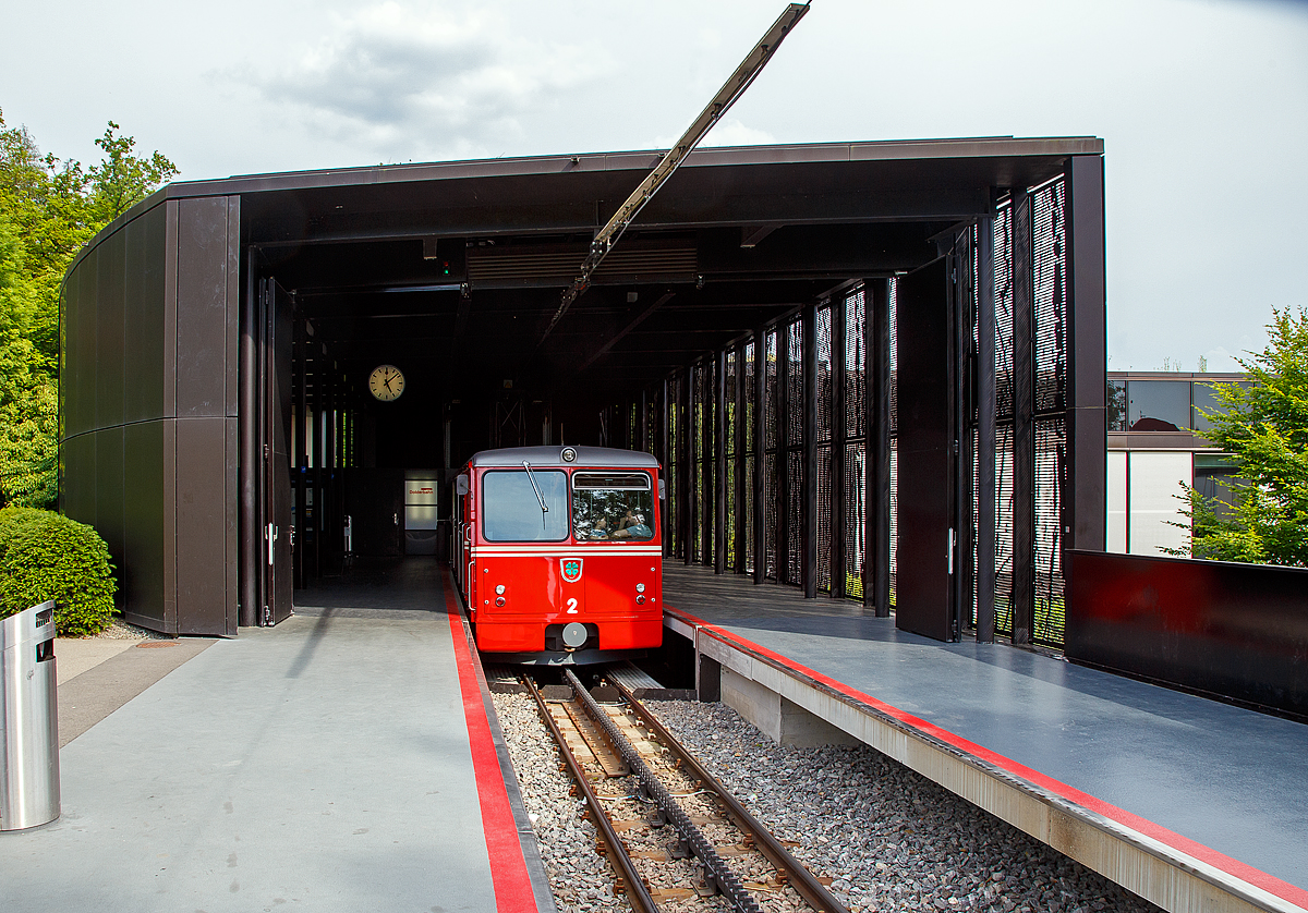 Der elektrischer Zahnradtriebwagen Bhe  1/2 Nr. 2 der Dolderbahn steht am 06.06.2015 in der Bergstation zur Talfahrt bereit

Die beiden Elektrischer Zahnradtriebwagen Bhe  1/2 der Dolderbahn
Im Jahr 1972 stellte die Dolderbahn- Betriebs AG den Seilbahnbetrieb ein, verlängerte die Strecke um rund 500 m auf 1,3 km und verlegte eine Lamellenzahnstange (System von Roll) in das erneuerte Gleis. Für den Zahnradbetrieb lieferte die SLM 1973 zwei zweiachsige Zahnradtriebwagen. Jeder dieser Zahnradtriebwagen hat talseitig eine Triebachse und bergseitig eine Bremsachse. Ein im Untergestell in Längsrichtung angeordneter Fahrmotor treibt über eine Kardanwelle und ein zweistufiges Getriebe das Triebzahnrad an. Die Verbundbauweise des Wagenkastens mit dem Untergestell ergibt eine selbsttragende, leichte und solide Konstruktion.  Volle Betriebssicherheit wird durch eine elektrische Widerstandsbremse, eine Zahnradbremse sowie eine Klinkenbremse gewährleistet.

TECHNISCHE DATEN:
Hersteller: SLM (Schweizerische Lokomotiv- und Maschinenfabrik), Winterthur
Elektrischen Ausrüstung: BBC (Brown, Boveri & Cie. AG), Baden
Spurweite: 1.000 mm (Meterspur)
Zahnstangensystem: von Roll
Achsformel: 2z
Max. Steigung: 196 ‰
Länge über Puffer: 11.520 mm
Achsabstand: 5.400 mm
Laufraddurchmesser: 690 mm
Teilkreisdurchmesser Treib- und Bremszahnrad: 573 mm
Eigengewicht: 14,4 t
Max. Zuladung: 7,8 t
Leistung: 131,5 kW (dauernd) / 149,5 kW (einstündig)
Zugkraft: 22,9 kN (dauernd) / 27,2 kN (einstündig)
Höchstgeschwindigkeit: 25 km/h (Bergfahrt) / 16 km/h (Talfahrt)
Getriebeübersetzung: 1 : 10,45
Sitzplätze: 26
Stehplätze: 74
Fahrdrahtspannung: 600 V = (DC)

Die Dolderbahn ist eine Privatbahn in der Stadt Zürich. Die Zahnradbahn erschließt das Dolder-Gebiet im Quartier Hottingen ab der Haltestelle Römerhof am Römerhofplatz auf 444 Metern über Meer und endet in der Station Dolder auf dem Adlisberg auf 606 Metern über Meer. Die Bahn dient nebst der Verbindung mit dem Wohnquartier auch als Zubringer für zwei Hotels, dem Wellenbad Dolder, der offenen Eisbahn Dolder und dem als Naherholungsgebiet dienenden Adlisberg.

Die Betreibergesellschaft wurde 1893 gegründet. 1895 wurde der Betrieb als Standseilbahn aufgenommen. Sie führte auf einer Strecke von rund 800 Metern vom Römerhofplatz zum Hotel Waldhaus Dolder auf 548 Metern über Meer.

Zur Verbindung mit dem Grand Hotel Dolder wurde am 5. Juli 1899 ein meterspuriges Tram in Betrieb genommen. Es wurde mit einem einzigen Wagen gleicher Bauart wie die StStZ-Wagen 57–84 betrieben. Die Strecke hatte keine direkte Verbindung zum Zürcher Tramnetz, jedoch sorgte die StStZ für den Unterhalt des Motorwagens und stellte während einer längeren Revision einen Ersatzwagen. Am 31. Dezember 1930 wurde das Dolder-Tram eingestellt und ein Bus übernahm die Verbindung zwischen Waldhaus und Grand Hotel.

Zwischen 1972 und 1973 wurde die Standseilbahn durch eine Zahnradbahn ersetzt und die Strecke bis zum Grand-Hotel Dolder verlängert. Weil dazu eine Kurve nötig war, wurde aus der Seil- eine Zahnradbahn. Seither misst sie 1.328 Meter und überwindet dabei eine Höhendifferenz von 162 Metern mit einer Neigung von maximal 19,6 Prozent. Weitere Vorteile gegenüber einer Standseilbahn sind, die Bahntrasse kann besser dem Gelände angepasst werden, die Ausweichstelle muß nicht genau in der Mitte der Bahnstrecke liegen. Zudem ist ein Einwagenbetrieb oder ein späterer Ausbau für automatischen Betrieb möglich.