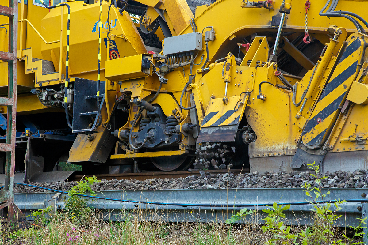 
DETAIL-Bild:
Die Plasser & Theurer Schnell-Schotterplaniermaschine SSP 110 SW,  Schweres Nebenfahrzeug Nr. D-DGU 99 80 9425 069-8 (ex 97 16 46 519 18-3), am 18.08.2019 auf der Dillstrecke (KBS 445) bei Wilnsdorf-Rudersdorf im Einsatz.
Der zwischen den Schienen abgekehrte Schotter wird im seitlichen Gleisbett begelegt.
