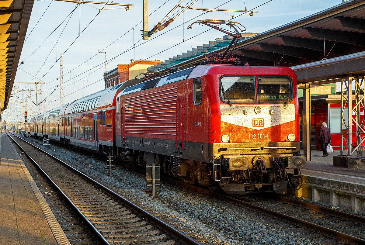 Die 112 101-1 (91 80 6112 101-1 D-DB) der DB Regio Nordost steht am 14.05.2022, mit dem RE 5 (Rostock – Stralsund – Berlin – Wünsdorf-Waldstadt), im Hbf Rostock zur Abfahrt bereit.

Die Lok wurde 1992 von AEG in Hennigsdorf unter der Fabriknummer 21477 gebaut und an die Deutsche Reichsbahn als DR 112 101-1 geliefert. Aus der Hennigsdorfer Lokschmiede LEW - VEB Lokomotivbau Elektrotechnische Werke „Hans Beimler“ Hennigsdorf wurde wieder von der AEG übernommen. DB und DR bestellten jeweils 45 Lokomotiven der Baureihe 112.1. Die an die DR gelieferten Maschinen bekamen die Betriebsnummern 112 101-1 – 112 145-8, die an die DB gelieferten die 112 146-6 – 112 190-4. Nach dem Zusammenschluss der beiden deutschen Bahnen zum 01.01.1994 zur DB AG wurden aus den DR Maschinen DB, so auch die 112 101-1.
