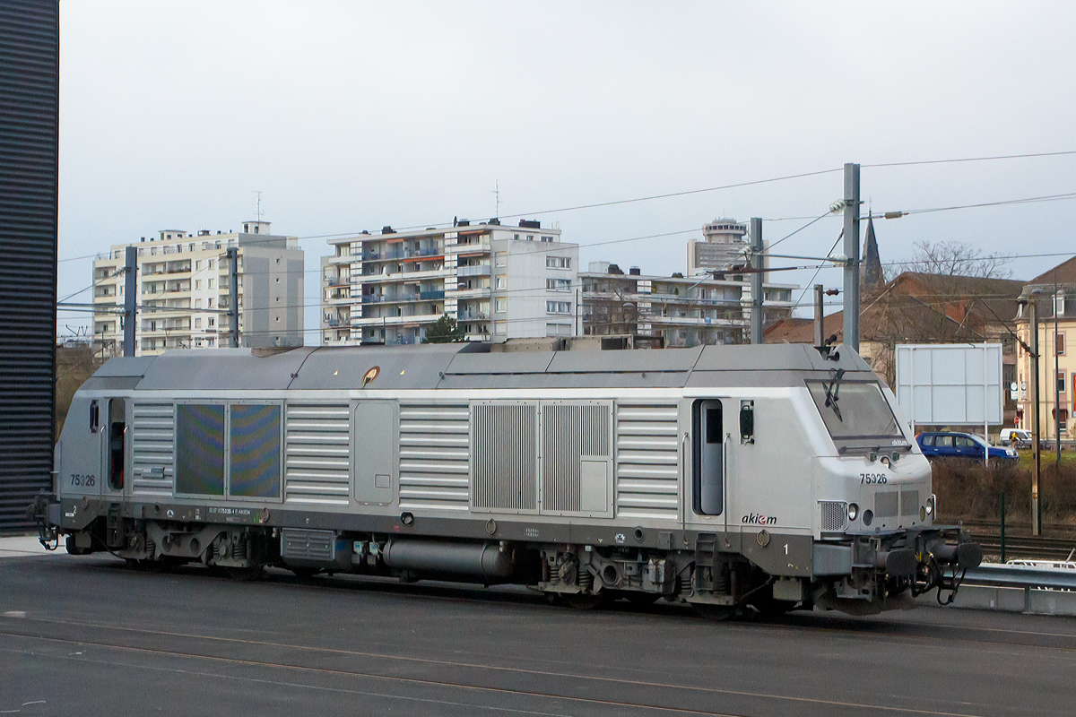 
Die Akiem BB 75 326 (92 87 0075 326-4 F-AKIEM), ex Akiem 75026, ex Fret SNCF 475026, ist am 24.03.2015 bei Muhlhouse (Mülhausen) abgestellt. Die Aufnahme konnte ich aus unserem Zug (TGV) heraus machen.

Die Alstom Prima DE33 B AC (BB 75000) wurde 2007  von Alstom für die Fret SNCF gebaut und als 475026 geliefert. Im Jahr 2011 wurde sie an die SNCF Tochtergesellschaft Akiem S.A.S. (eine französische Leasinggesellschaft für Lokomotiven) übertragen. Im August 2014 wurde sie modifiziert und in 75326 umgezeichnet. 

Durch die Modifizierung kann die Lok für Intercity Nachtzüge verwendet werden, für diese sind die modifizierten Loks der Baureihe BB 75 300 von der SNCF ab Dezember 2015 vorgesehen. Zurzeit sind sie aber noch meist vermietet, wie diese an die CFL Cargo Frankreich.

Die Loks basieren äußerlich weitgehend auf den verwandten Elektroloks der Alstom-Prima-Familie. Von diesen stammen Rahmen, Lokkasten, Führerstände, Drehgestelle, Antriebssystem und die pneumatischen Bremsen. Im Inneren ist viel Technik von Siemens Transportation Systems, von hier kommen die Komponenten Motor-System, Kühlung, Batterie und Hydraulik, welche weitgehend mit denen der Siemens ER 20 BU identisch sind. Aus Kapazitätsgründen werden auch die Kästen von 130 Loks bei Siemens in München gebaut, die Endmontage findet jedoch im Alstom-Werk im französischen Belfort statt, wo auch die restlichen Loks entstehen.

Anzahl:  
99 BB 75000 (davon 7 umgebaut in 75 300)
33 BB 75100 (Deutschland und Benelux tauglich)
167 BB 75400
Spurweite:  1435 mm (Normalspur)
Achsformel:  Bo'Bo'
Länge über Puffer:  20.280 mm
Drehzapfenabstand:  10.820 mm
Dienstmasse:  84 t
Radsatzfahrmasse:  21 t
Höchstgeschwindigkeit:  120 km/h
Installierte Leistung:  2000 kW
Traktionsleistung:  1600 kW
Anfahrzugkraft:  300 kN
Dauerzugkraft: 177 kN bei 32,5 km/h
Treibraddurchmesser:  1.150 mm
Dieselmotor:  MTU 16V 4000 R41 (ab 75401 MTU 16V 4000 R43L)
Tankinhalt:  4000 L
Antrieb:  dieselelektrisch
Fahrmotoren: 4 Stück Asynchronmotoren FRA 4567 6 
Bremse:  elektrische Widerstandsbremse
Kupplungstyp:  Schraubenkupplung
