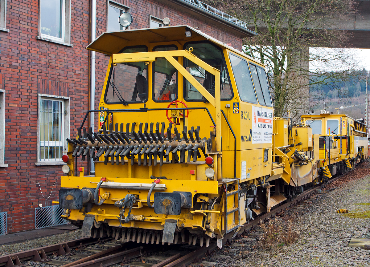 
Die Matisa Schotterplaniermaschine vom Tpy R 20 L (Schweres Nebenfahrzeug Nr. 97 16 38 501 17 – 3) und die Plasser & Theurer Zweischwellenstopfmaschine 09 - 32  CSM (Schweres Nebenfahrzeug Nr. 97 40 68  524 17 -9) beide von der Firma Hans Kaiser GmbH & Co. KG (Tann) abgestellt am 25.12.2014 am KSW Bahnhof Siegen-Eintracht (Betriebsbereich Eisern-Siegener Eisenbahn).

Die Schotterplaniermaschine wurde 1993 von MATISA Matriel Industriel S.A in Crissier (Schweiz) unter der Fabriknummer 6714 gebaut und an die Thringer Gleisbau geliefert.

Die modulare Baureihe R 20 wird bereits seit 1987 hergestellt, wir hier ist es Normalspur-Maschine. Entwickelt wurden diese Maschinen jedoch speziell fr Schmalspurnetze oder Netze mit begrenzter Achslast entwickelt. Der Schotterpflug der Baureihe R 20 kann in beide Fahrtrichtungen (Richtungsunabhngig) arbeiten, dies hat den Vorteil Leerfahrten der Maschine zu vermeiden und Schotterverschiebungen von einer Bettungsschulter zur anderen in einem einzigen Arbeitsdurchgang durchzufhren. Daraus ergibt sich ein bemerkenswerter Zeitgewinn, wobei meist das Stopfen den grten Zeitaufwand bentigt. Die groe Beweglichkeit der Seitenpflge ermglicht auch bei hohen Geschwindigkeiten das Umgehen von Hindernissen. Die Anpassung an alle Gleisschulterprofile und das Arbeiten im Seitenbereich der Gleise erfolgt ohne Verletzung des Lichtraumprofils des Nachbargleises.

Die vor der Kabine angeordneten Zentralpflge bleiben stets im Sichtbereich des Bedieners. Alle Maschinen sind mit einem doppelten Bedienungspult ausgerstet. Die reichlich dimensionierte Kabine bietet eine ausgezeichnete Sicht auf den Arbeitsbereich und das Gleis.

Die Brsteneinheit ist mit einem Aufnahmekasten ausgerstet, der den wegschleudernden Schotter aufnimmt und auf ein Frderband leitet, das ihn entweder seitlich auf die Gleisschultern wirft (Version L) oder in einen Silo befrdert (Version LS und LT).

Technische Daten der Schotterplaniermaschine R 20 L:
Spurweite: 1.435 mm (lieferbar 1.000 bis 1.676 mm)
Achsanzahl: 2
Achsabstand: 6.200 mm
Lnge ber Puffer: 13.690 mm
Eigengewicht: 28,5 t
Anhngelast: 20 t
Zur Mitfahrt zugel. Personen: 2
Hchstgeschwindigkeit: 90 km/h
Max. Geschwindigkeit beim Planieren: 12 km/h
Max. Geschwindigkeit beim Kehren: 3 km/h
Kleinster befahrbarer Kurvenradius: R 75 m
Motor: DEUTZ-Dieselmotor vom Typ F 10 L 413 F
Motorleistung: 196 kW / 2300 U/min