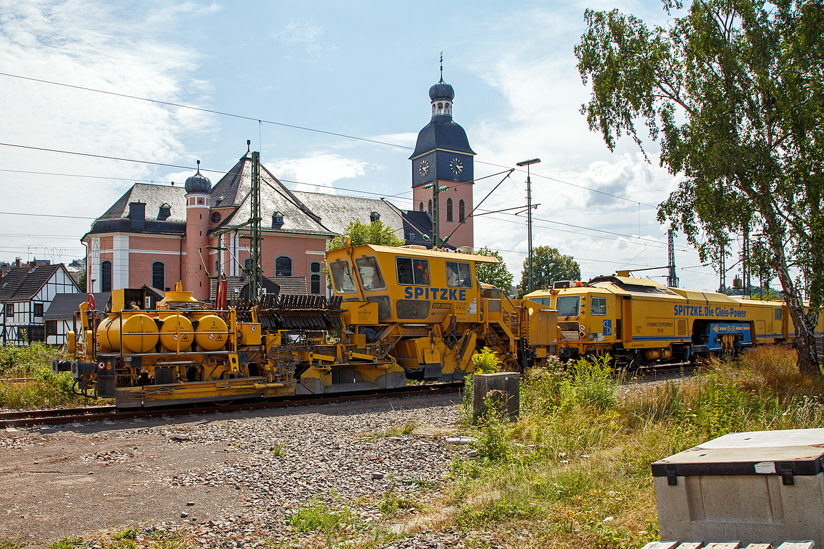 
Die Plasser & Theurer Schotterverteil- und Planiermaschine SSP 2000 der SPITZKE SE, Schweres Nebenfahrzeug Nr. D-SPAG 99 80 9125 007-1, abgestellt am 21.07.2018 in Wissen (Sieg). Dahinter die Plasser & Theurer Dreischwellenstopfmaschine 09-3X Dynamic  der SPITZKE SE, Schweres Nebenfahrzeug Nr. D-SPAG 99 80 9121 006-7.

Die Schnellschotterplaniermaschine SSP 2000 stellt den erforderlichen Regelbettungsquerschnitt in Gleisen und Weichen her. Die Maschine verfüllt, planiert und kehrt das Gleis. Sie verfügt über Besenwellen für alle Oberbauformen.

Funktionsmerkmale:
- Automatische Ausschwenkbegrenzungen der Flankenpflüge verhindern ein Überschreiten des Regellichtraumprofils
- Besenwellenschnellwechselvorrichtung
-  Zwei durchgehende Achsen als Triebachsen
- Durch Schraubenfedern und Stoßdämpfer wird eine ausreichende Absorption von Schwingungen und Stößen und eine große Laufruhe des Fahrzeuges erreicht
- Geschlossene schallisolierte Großraum-, Fahr- und Arbeitskabine am hinteren Teil der Maschine
-  Zwei waagerecht und senkrecht verstellbare Flankenpflüge im vorderen Teil der Maschine
- Mit Planierpflugeinrichtung für schwerste Schotterarbeiten – bestehend aus zwei voneinander unabhängig absenkbaren in Gleisrichtung laufenden Pflughälften
- Kehranlage inklusive einer Kehrbürste und einem Querförderband zur Verfüllung der Zwischenfächer bzw. Ableitung des überflüssigen Schotters auf das Querförderband
- Drehzahl des Bürstenantriebes kann bis max. 350 U/min stufenlos verstellt werden
- Schotterentfernung zwischen Schiene und Kleineisen durch zwei Kleineisenbürsten hinter der Vorderachse
- Ausgerüstet mit Sifa und Indusi


TECHNISCHE DATEN der SSP 2000:
Spurweite: 1.435 mm
Achsformel: A´A´
Länge über Puffer: 17.000 mm
Achsabstand: 10.000 mm
Eigengewicht: 40,3 t
Anhängelast: 60 t
Leistung: 400 kW
Höchstgeschwindigkeit: 100 km/h (Eigenfahrt und geschleppt)
Zugelassen zur Mitfahrt:  4 Personen
Kleinster befahrbarer Kurvenradius:  R 90 m (Arbeitsradius  120 m)     
Zugelassen für Streckenklasse: C2 oder  höher
Bremse: KE-GP mZ
Bremsgewichte: G = 26 t / P = 26 t
Tankvolumen: 2x 1.000l Diesel
Wasservorrat: 1.000 l (für Sprühnebel bei Staubanfall)

Besonderheiten: 5-fach verstellbarer Mittelpflug, Ausschwenkbegrenzung für Pflüge auf mehrgleisigen Strecken

Leistungsparameter
Arbeitsleistung bei Durcharbeitung des Gleises: max. 1.600 m/h
Arbeitsleistung bei Umbau des Gleises: max. 1.200 m/h
Arbeiten in Überhöhung: max. 180 m

Quelle: http://www.technikpark.com (SPITZKE SE), sowie Anschreibungen am Fahrzeug.