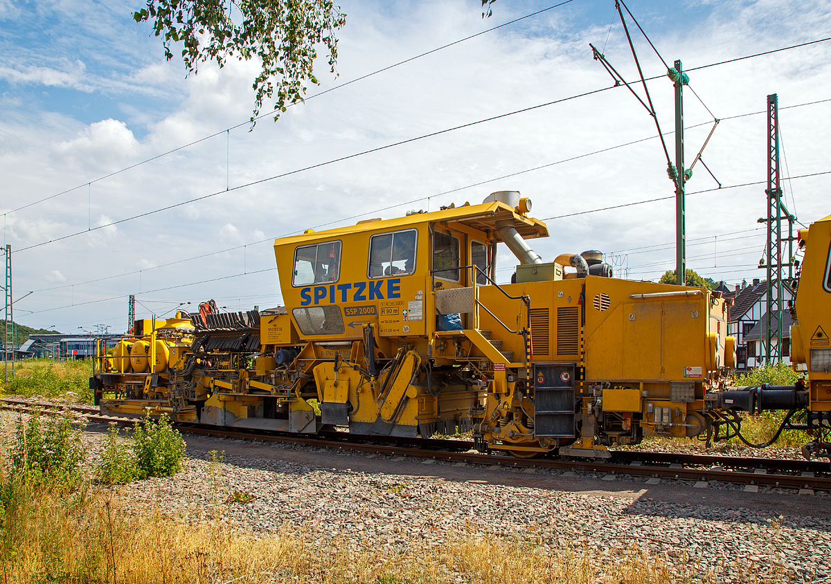 
Die Plasser & Theurer Schotterverteil- und Planiermaschine SSP 2000 der SPITZKE SE, Schweres Nebenfahrzeug Nr. D-SPAG 99 80 9125 007-1, abgestellt am 21.07.2018 in Wissen (Sieg).

Die Schnellschotterplaniermaschine SSP 2000 stellt den erforderlichen Regelbettungsquerschnitt in Gleisen und Weichen her. Die Maschine verfüllt, planiert und kehrt das Gleis. Sie verfügt über Besenwellen für alle Oberbauformen.

Funktionsmerkmale:
- Automatische Ausschwenkbegrenzungen der Flankenpflüge verhindern ein Überschreiten des Regellichtraumprofils
- Besenwellenschnellwechselvorrichtung
-  Zwei durchgehende Achsen als Triebachsen
- Durch Schraubenfedern und Stoßdämpfer wird eine ausreichende Absorption von Schwingungen und Stößen und eine große Laufruhe des Fahrzeuges erreicht
- Geschlossene schallisolierte Großraum-, Fahr- und Arbeitskabine am hinteren Teil der Maschine
-  Zwei waagerecht und senkrecht verstellbare Flankenpflüge im vorderen Teil der Maschine
- Mit Planierpflugeinrichtung für schwerste Schotterarbeiten – bestehend aus zwei voneinander unabhängig absenkbaren in Gleisrichtung laufenden Pflughälften
- Kehranlage inklusive einer Kehrbürste und einem Querförderband zur Verfüllung der Zwischenfächer bzw. Ableitung des überflüssigen Schotters auf das Querförderband
- Drehzahl des Bürstenantriebes kann bis max. 350 U/min stufenlos verstellt werden
- Schotterentfernung zwischen Schiene und Kleineisen durch zwei Kleineisenbürsten hinter der Vorderachse
- Ausgerüstet mit Sifa und Indusi


TECHNISCHE DATEN der SSP 2000:
Spurweite: 1.435 mm
Achsformel: A´A´
Länge über Puffer: 17.000 mm
Achsabstand: 10.000 mm
Eigengewicht: 40,3 t
Anhängelast: 60 t
Leistung: 400 kW
Höchstgeschwindigkeit: 100 km/h (Eigenfahrt und geschleppt)
Zugelassen zur Mitfahrt:  4 Personen
Kleinster befahrbarer Kurvenradius:  R 90 m (Arbeitsradius  120 m)     
Zugelassen für Streckenklasse: C2 oder  höher
Bremse: KE-GP mZ
Bremsgewichte: G = 26 t / P = 26 t
Tankvolumen: 2x 1.000l Diesel
Wasservorrat: 1.000 l (für Sprühnebel bei Staubanfall)

Besonderheiten: 5-fach verstellbarer Mittelpflug, Ausschwenkbegrenzung für Pflüge auf mehrgleisigen Strecken

Leistungsparameter
Arbeitsleistung bei Durcharbeitung des Gleises: max. 1.600 m/h
Arbeitsleistung bei Umbau des Gleises: max. 1.200 m/h
Arbeiten in Überhöhung: max. 180 m

Quelle: http://www.technikpark.com (SPITZKE SE), sowie Anschreibungen am Fahrzeug.
