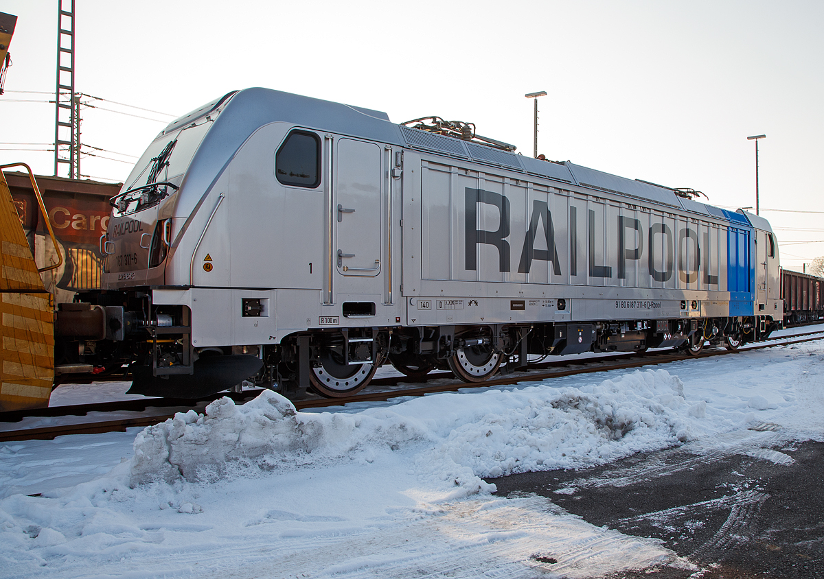 Die RAILPOOL 187 311-6 (91 80 6187 311-6 D-Rpool), eine Bombardier TRAXX F140 AC3 LM auch bekannt als Last-Mile-Lokomotive, abgestellt am 22.01.2016 beim ICE-Bahnhof Montabaur.

Die TRAXX F140 AC3 LM wurde 2016 von Bombardier gebaut. Nach meiner Sichtung hat die Lok die Zulassung für Deutschland und Österreich. Für Ungarn und Rumänien sind die Zulassungen noch nicht erteilt (H und RO sind durchgestrichen).

Die TRAXX F140 AC LM ist eine vierachsige Lokomotive mit einer Leistung von 5.600 kW für den grenzüberschreitenden Einsatz. Die Lokomotive befördert hauptsächlich Güterzüge auf den europäischen Hauptstrecken, die mit 15 kV oder 25 kV elektrifiziert sind. Die Höchstgeschwindigkeit beträgt 140km/h. Die Lokomotiven können in gemischter Mehrfachtraktion mit BR185 und BR186 eingesetzt werden.

Mehr als 2.140 TRAXX-Lokomotiven wurden bisher weltweit verkauft. Ihr modularer Aufbau macht sie so einzigartig: In rund 70 Prozent ihrer Bauteile sind alle TRAXX-Loks identisch. Sie sind 18,9 Meter lang, haben die gleichen Drehgestelle, Traktionsmotoren, Führerstände und Kommunikationssysteme. TRAXX-Lokomotiven fahren je nach Bedarf grenzüberschreitend und sind in 19 Ländern zugelassen. Die Baureihe 187 ist die erste Variante der Traxx-3-Reihe. Die interne Bezeichnung von Bombardier für die Baureihe 187 lautet Traxx F140 AC3 LM.

Die Endmontage der Lokomotiven erfolgt im Bombardier-Werk Kassel, einem Teil des ehemaligen Henschel-Werkes. Die Wagenkästen kommen aus Wrocław (Polen), die Drehgestelle aus Siegen. Antriebs-, Steuerungs- und Sicherheitssysteme werden in Mannheim und Hennigsdorf sowie in Västeras (Schweden) hergestellt.

Die Baureihe 187 ( Traxx F140 AC3 LM) wurde von Bombardier auf der Messe Transport und Logistik im Mai 2011 in München erstmals präsentiert. Die BR 187 ist eine für 15 kV 16,7 Hz und 25 kV 50 Hz Wechselstrom ausgerüstete Lokomotive, die mit einem 180 kW starken Dieselhilfsmotor  vom Typ Deutz TCD2013 4V ausgestattet ist, um auch Streckenabschnitte ohne Oberleitung (Last Mile) befahren zu können. Im Dieselbetrieb werden alle vier Fahrmotoren betrieben; die Anfahrzugkraft ist dabei genauso hoch wie bei elektrischem Betrieb. Ohne Anhängelast kann eine Lokomotive der Baureihe 187 mit ihrem Dieselmotor eine Höchstgeschwindigkeit von 60 km/h erreichen; ein 2.000 Tonnen schwerer Zug kann noch auf 40 km/h beschleunigt werden. Der Diesel-Hilfsmotor verfügt über einen Hubraum von 7.150 cm³ und erfüllt die Stage-IIIB-Abgasnorm. Der Tankinhalt von 400 Litern reicht für bis zu acht Stunden Dieselbetrieb, kurze Strecken können auch ausschließlich mit der eingebauten Batterie zurückgelegt werden. Der Übergang von elektrischer Traktion zu Dieseltraktion kann während der Fahrt erfolgen. Für den Rangierbetrieb ist eine Funkfernsteuerung erhältlich.

Mit der Last Mile Funktion gehört der Wechsel der von elektrischer Lokomotive hin zu Rangier- oder regulärer Diesellok auf nicht-elektrifizierten Streckenabschnitten der Vergangenheit an. Das erhöht die Flexibilität etwa an Systemwechselbahnhöfen, Terminals, Werksbahnhöfen oder Häfen und somit die Effizienz des Schienenverkehrs. Das Dieselaggregat erfüllt die Stage IIIB/VERT-Anforderungen für emissionsarme Motoren, ist also ausgesprochen umweltfreundlich. Er erreicht bei geringer Geschwindigkeit maximale Zugkraft.

Die Baureihe 187 mit Last-Mile-Diesel ist mit Stand März 2016 in Deutschland, Österreich, der Schweiz, Bulgarien und Kroatien zugelassen. 

Die Seitenflächen der Baureihe 187 verfügen über eine Vorrichtung zum Einspannen von Planen, auf denen Werbung angebracht werden kann

In die Entwicklung flossen Erfahrungen der in den USA eingesetzten Zweikraftlokomotive ALP-45DP ein. Erster Besteller dieser Lokomotiven war Ende 2010 der Fahrzeugvermieter Railpool mit fünf Exemplaren. Drei von diesen wurden an die BLS Cargo vermietet, die sie in Deutschland, Österreich und der Schweiz einsetzt. 

Im März 2014 wurden erste Fahrten im Rahmen des Zulassungsverfahren absolviert. Die Baureihe 187 mit Last-Mile-Diesel ist mit Stand März 2016 in Deutschland, Österreich, der Schweiz, Bulgarien und Kroatien zugelassen.

Im Mai 2013 gab die Deutsche Bahn AG bekannt, einen Rahmenvertrag mit Bombardier unterzeichnet zu haben, welcher die Lieferung von bis zu 450 weiteren elektrischen Traxx-Lokomotiven verschiedener Bauarten vorsieht.
Auf Grund der Ausschreibungsbedingungen musste Bombardier umfangreiche Änderungen an der Traxx 3 vornehmen. Insbesondere die Drehgestelle der neuen Version P189AC (Höchstgeschwindigkeit 160 km/h, optional 189 km/h) unterscheiden sich deutlich von denen der Baureihe 187.

Erste der Bestellungen (der DB):
Aus diesem Rahmenvertrag rief die Deutsche Bahn Tag 110 Fahrzeuge für DB Cargo (als Baureihe 187.1) sowie 20 Traxx P160AC3 für DB Regio (als Baureihe 147) ab.

Der Einbau einer Last-Mile-Einrichtung ist möglich, aber nach derzeitigen Planungen ist aber für den großen Rahmenvertrag von bis zu 450 Lokomotiven kein Einbau des Dieselmotors vorgesehen.
Weitere Aufträge:
Die israelische Staatsbahn bestellte im August 2015 zunächst 62 Lokomotiven mit einer Option über bis zu 32 weitere Exemplare. Die Lokomotiven mit einer Leistung von sechs Megawatt unter 25 Kilovolt kommen auf dem neu elektrifizierten Netz Israels zum Einsatz

TECHNISHE DATEN der BR 187 (TRAXX F140 AC3 LM)
Hersteller: 	Bombardier Transportation
Spurweite: 	1.435 mm (Normalspur)
Achsanordnung: Bo’Bo’
Länge über Puffer: 18.900 mm
Drehzapfenabstand:  10.440 mm
Achsabstand im Drehgestell: 2.600 mm
Treibraddurchmesser: 	1.250 mm (neu) / 1.170 mm (abgenutzt)
Höhe:  4.283 mm
Breite:  2.977 mm
Lichtraumprofil: UIC 505-1
Dienstgewicht:  87 t
Fahrmotoren: 4 Asynchronmotoren
Bremse: Elektrische Bremse

Daten im Oberleitungsbetrieb:
Höchstgeschwindigkeit:  140 km/h
Dauerleistung: 5.600 kW
Anfahrzugkraft: 300 kN
Dauerzugkraft: 252 kN bei 80 km/h
Stromsystem:  15 kV 16,7 Hz~ und 25 kV 50 Hz~

Daten im Dieselbetrieb (Last-Mile):
Motor: Wassergekühlter Deutz 6-Zylinder Reihen-Dieselmotoren mit Turboaufladung und Ladeluftkühlung vom Typ TCD 2013 L6 4V (Der Motor ist aus der Großserienproduktion)
Nenndrehzahl: 1.800 – 2.000 U/min
Motorhubraum: 7.150 cm³
Abgasnorm: Stage-IIIB
Motorgewicht: ca. 650 kg
Höchstgeschwindigkeit:  60 km/h
Dauerleistung: 180  kW (245 PS)
Anfahrzugkraft: 260 kN (Last Mile)
Tankinhalt:  400 l

Zugsicherung: 	GSMR Zugfunk, ETCS, PZB, LZB, ZUB, Signum
