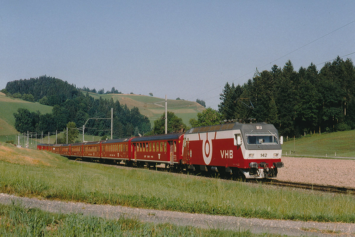 Die Re 456 142 der Vereinigten Huttwil Bahnen VHB mit einem aus zehn Wagen bestehenden Sonderzug bei Gondiswil unterwegs im Sommer 1984. 
Normalerweise war diese starke Lok nur vor schweren Güterzügen zur sehen. 
Kurz nach der Fusion zur RM hat die SOB die Re 456 142-143 angemietet.
Die VHB ist längst Geschichte.
Foto: Walter Ruetsch 