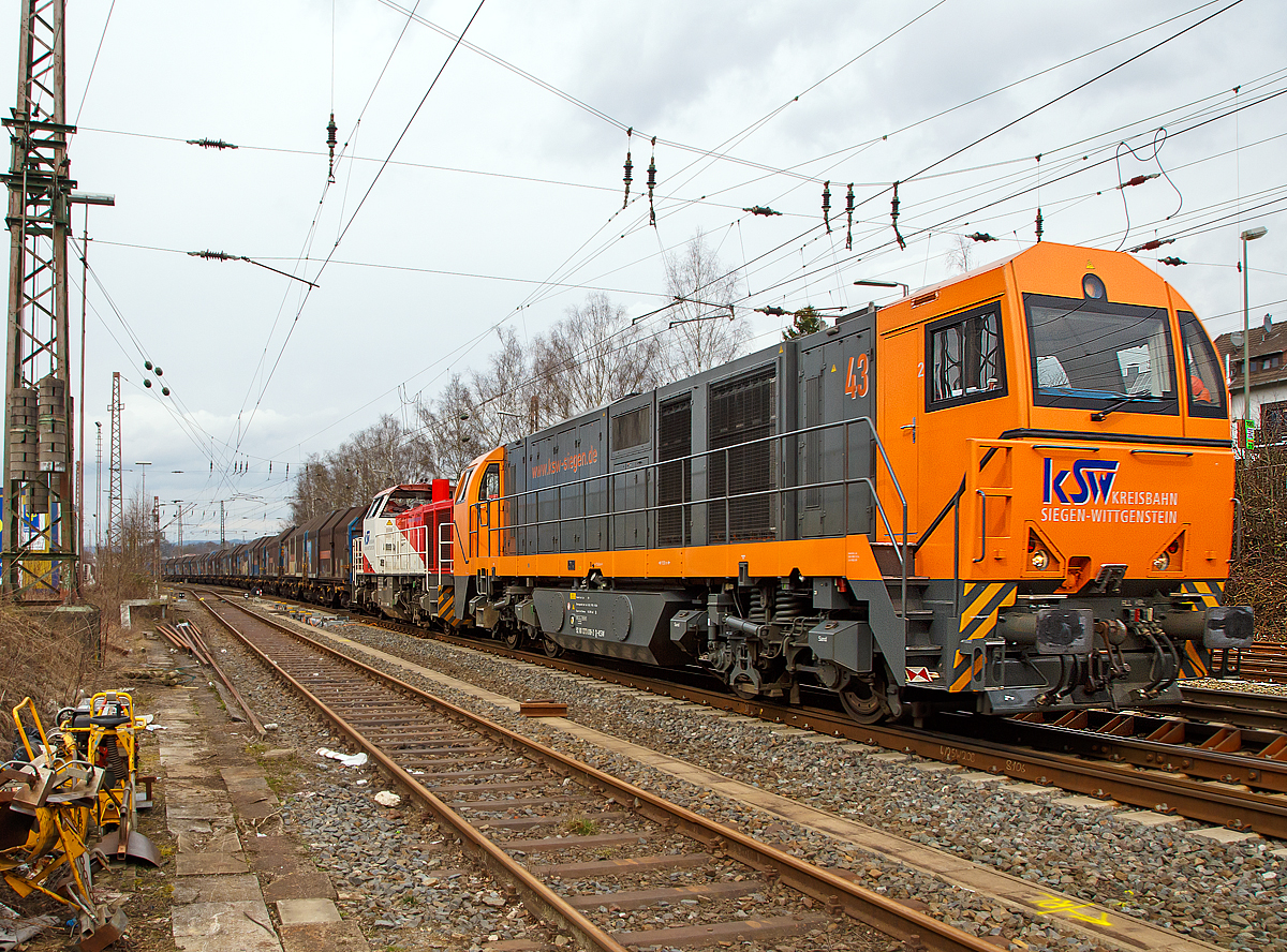 
Ein langer Coilzug fürs Hellertal und eine ungewöhnliche Doppeltracktion.....
Die Kreisbahn Siegen-Wittgenstein (KSW) Lok 43 (92 80 1273 018-2 D-KSW), eine Vossloh MaK G 2000 BB und die Lok 47 (92 80 1271 027-5 D-KSW), ex D 2 der HFM, eine Vossloh G 1000 BB, rauschen am 17.03.2017 mit einem langen Coilgüterzug durch Kreuztal in Richtung Siegen. 

Über Siegen, Betzdorf/Sieg und Herdorf geht es nach Neunkirchen-Salchendorf zum Pfannenberg. Wobei in Herdorf der Zug geteilt und die Lok meist gewechselt wird. 

Die KSW holt täglich Coils aus dem Duisburger Hafen ins südliche Siegerland. Auf einem solchen Drehgestell-Flachwagen mit Teleskophauben der Gattung Shimmns² befinden sich jeweils 4 Coils (kaltgewalztes Blech aufgerollt zu Rollen). Wenn man es über die Straße fahren wöllte bräuchte man für jeden Wagon gleich vier LKW´s. Zudem kann man einen jährlichen Anstieg der Tonnagen beobachten.

Die Doppeltracktion ist wohl auf der Ruhr-Sieg-Strecke auch nötig, die Steigung im Sauerland beträgt zwar nur 12 ‰, ist aber sehr lang und kurvenreich.  Daher sind häufige Geschwindigkeitswechsel notwendig.

Noch heute werden schwere Güterzüge auf der Ruhr-Sieg-Strecke in Richtung Süden zwischen Lennestadt-Altenhundem und Welschen Ennest mit einer zusätzlichen Lok nachgeschoben. Diese fährt danach wieder zurück nach Lennestadt-Altenhundem. Vor der Elektrifizierung der Ruhr-Sieg-Strecke wurden fast alle Güterzüge bis Welschen Ennest nachgeschoben. Seltener hatten und haben Güterzüge ab Kreuztal bis Welschen Ennest diese Unterstützung.
