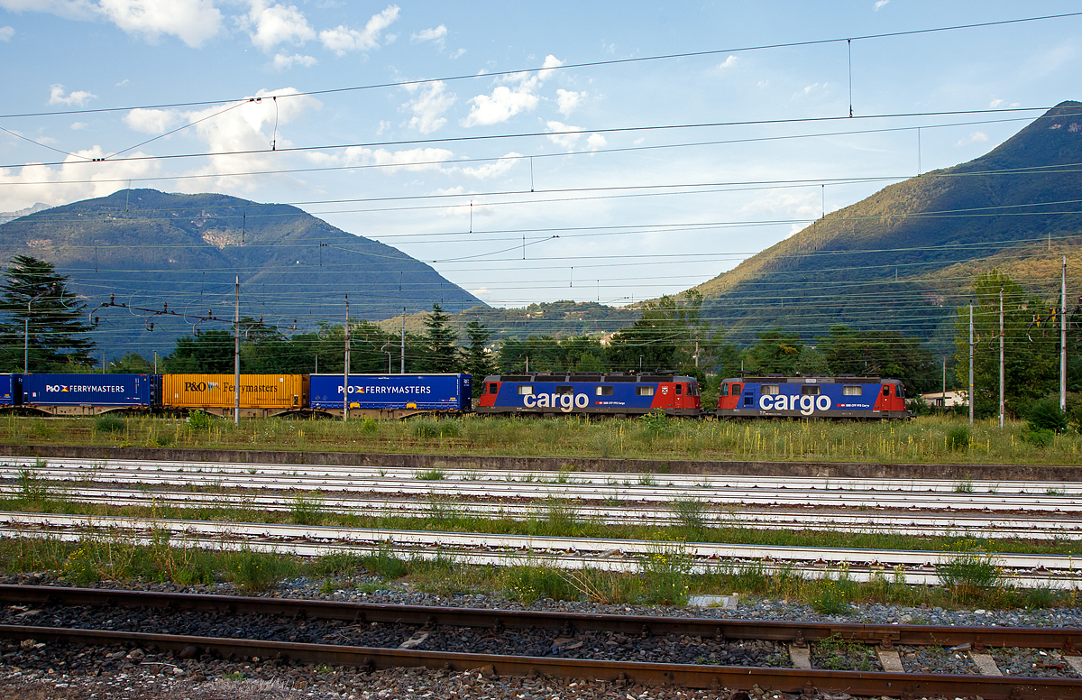 Eine SBB Cargo Re 10/10, bestehend aus der Re 420 344-4 (Re 4/4 – 11 344) und der Re 620 086 (Re 6/6 - 11686 „Hochdorf“), fährt am 04.08.2019 mit einem Container-Zug über die einspurige Güterzugumfahrung Domodossola zum Rangierbahnhof Beura-Cardezza (ex Bahnhof Domodossola II). Diese Strecke ist mit 15 kV 16,7 Hz Wechselstrom elektrifiziert.