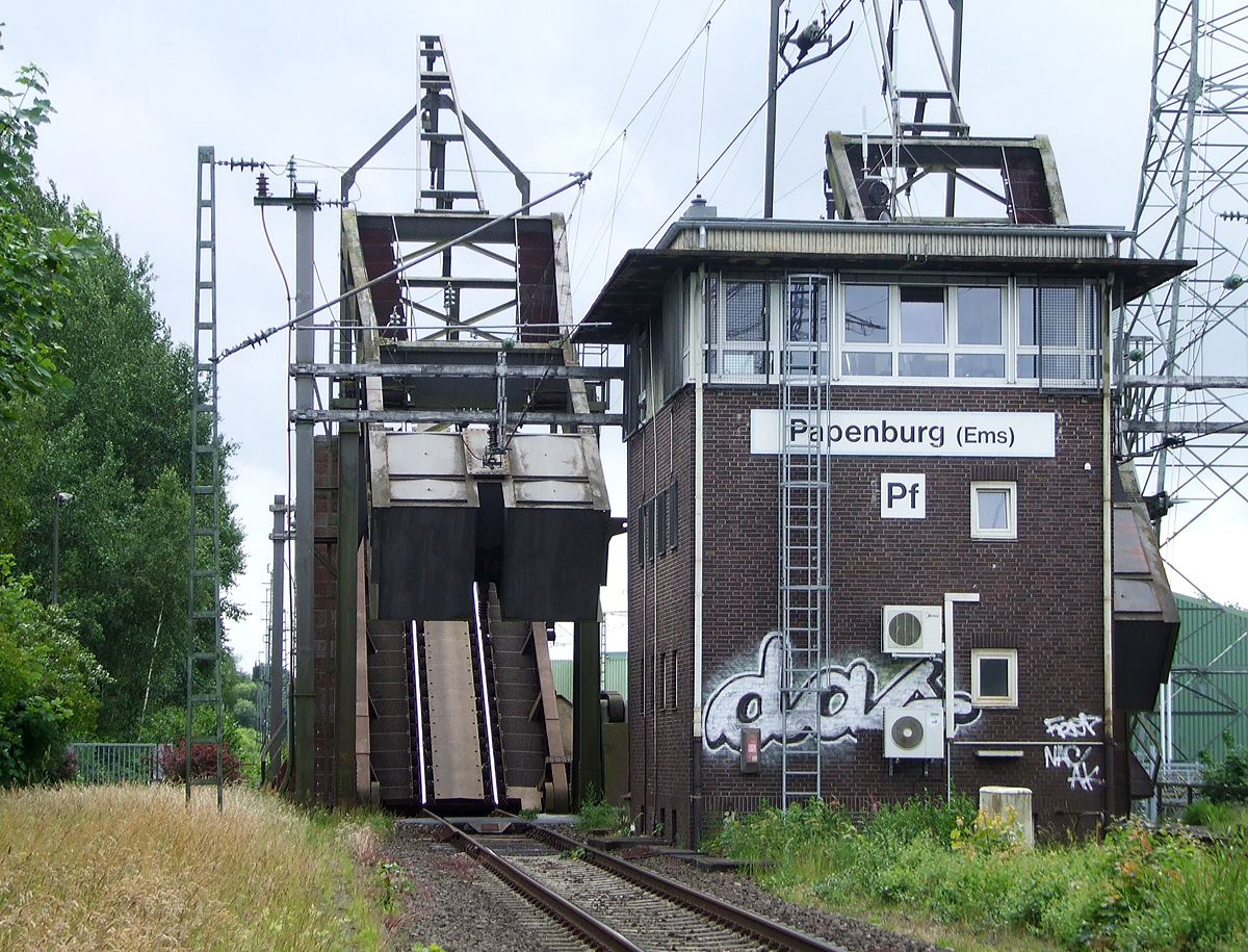 
Gleich vor dem Bahnhof Papenburg (Ems) befindet sich die Eisenbahnklappbrücke über den Papenburger Sielkanal, davor noch das Fahrdienstleiterstellwerk Papenburg (Ems) „Pf“, hier am 20.06.2009.

Die beiden Brückenteile werden gerade wieder abgesenkt.