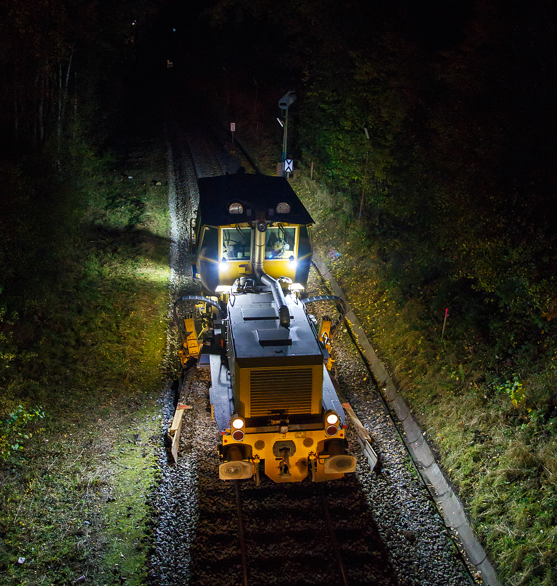 
Im Gleisbau wird Tag und Nacht gearbeitet, wie hier beim 3. Durchgang beim Stopfen  der Hellertalbahn (KBS 462) zwischen Neunkirchen und Herdorf. Die Plasser & Theurer Schotterverteil- und Planiermaschine SSP 110 SW, Schweres Nebenfahrzeug Nr. D-DGU 99 80 9425 068-0, ex 97 16 46 516 18-9 D-DGU (ex Hering Gleisbau, ex Volker-Rail), folgt hier am Abend des 27.10.2020 in Neunkirchen-Altenseelbach der Stopfmaschine.