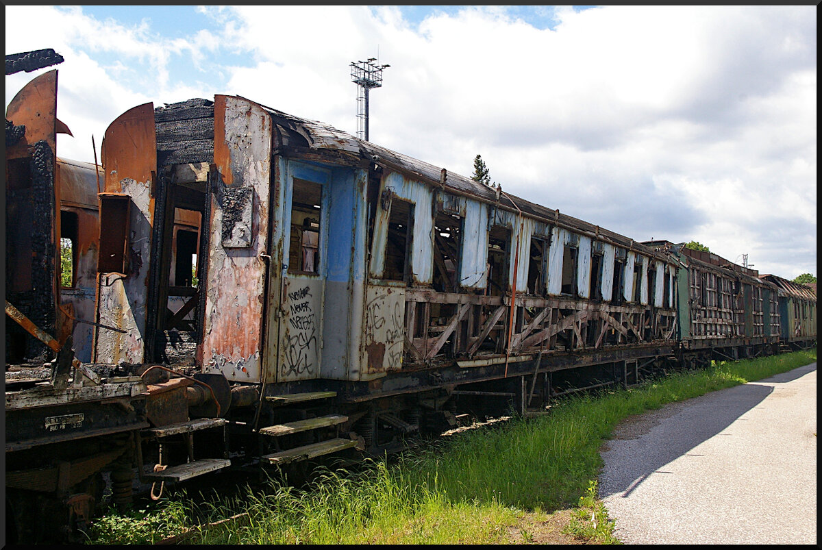 Im innern dieses Schnellzugwagen(?) wurde auch Feuer gelegt und hat ihn stark beschädigt, so das er nur noch mit einem Spanngurt zusammengehalten werden kann. Eine ČSD-Nummer war auch am Rahmen nicht mehr erkennbar. Der Wagen steht auf einem Abstellgleis im Eisenbahnmuseum Jaroměř.

Jaroměř, 21.05.2022
