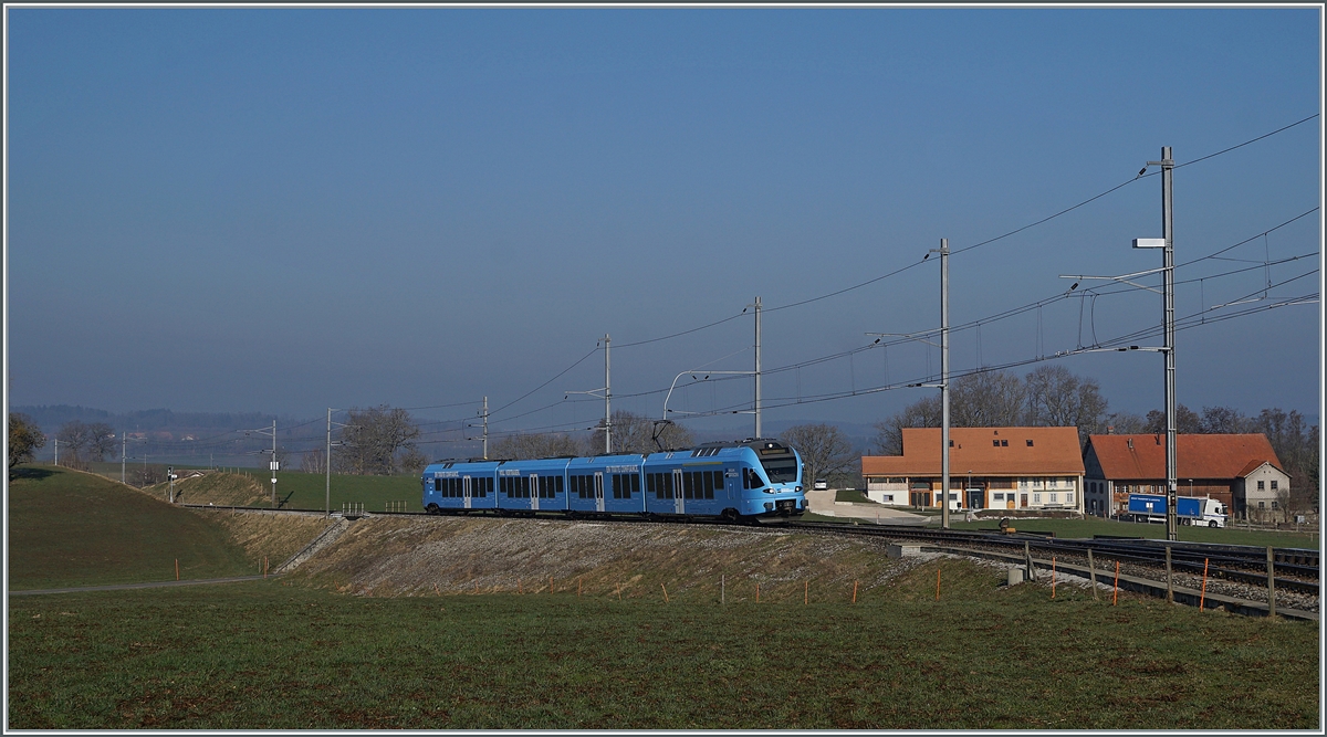 In weiten Kurven windet sich das Trasse der Strecken von Romont nach Vuisternens-devant- Romont, um die gut achzig Höhenmeter zu überwinden. Der im sehr gefälligen Werbeanstrich der  Groupe Grisoni  gehaltene TPF RABe 527 198 hat die Steigung fast geschafft und erreicht in Kürze den Bahnhof Vuisternas-devant-Romont, welcher jedoch wie alle Station zwischen Romont und Bulle nur noch dienstlichen Zwecken dienen.

1. März 2021