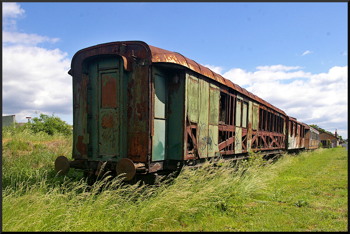 Langsam wächst Gras über den entkernten Schnellzugwagen, der im Eisenbahnmuseum Jaroměř auf einem der äußeren Seitengleise abgestellt ist. Da auch seine äußeren Bleche und Fenster fehlen, konnte die Witterung ihr Werk tun und so sieht er schon leicht schief und krumm aus.

Jaroměř, 21.05.2022
