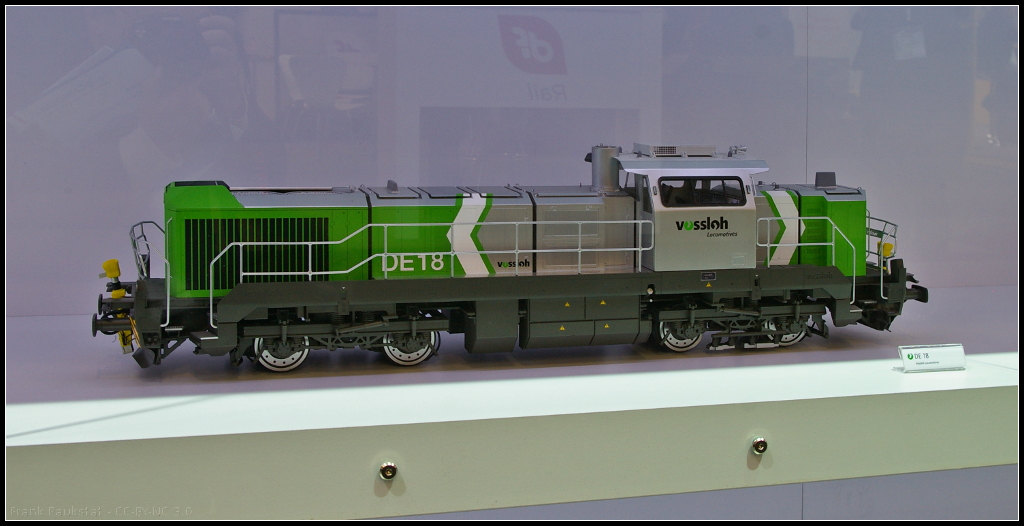 Model of Vossloh DE 18 diesel electric locomotive.
<br /><br />
Bei der DE 18 von Vossloh handelt es sich um eine Lokomotive f�r den Frachtverkehr. Die Lok bietet eine Leistung von maximal 1800 kW und eine Start-Stopp-Automatik (VED) sowie ein Fahrer-Assistenzsystem. Zuk�nftig sollen auch Hybrid- und Speichertechnik m�glich sein. Das Modell war w�hrend der InnoTrans 2014 n Berlin am Messestand von Vossloh ausgestellt.
<br /><br />
Webseite Daten (deutsch): http://www.vossloh-locomotives.com/de/products_and_services/diesel-hydraulic_locomotives/de12_de18/de12_de18.html
