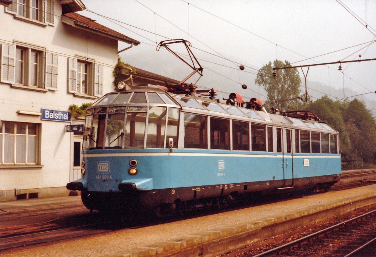 OeBB/DB: An Christi Himmelfahrt feiern die Mnner in Deutschland und Oesterreich den Vatertag. Vor 33 Jahren gnnten sich deutsche Eisenbahnfreunde zu diesem besondern Anlass mit dem Glsernen Zug eine Sonderfahrt nach Balsthal zur Oensingen Balsthal Bahn. Dieser spezielle Zug mit Baujahr 1935 ist im Jahre 1995 bei einem Zugsunglck leider derart stark beschdigt worden, dass er im Jahre 1997 ausgemustert werden musste. DB 491 001-4 ex DR ET 9101 vor dem Bahnhof Balsthal an Christi Himmelfahrt im Juni 1982.
Foto: Walter Ruetsch