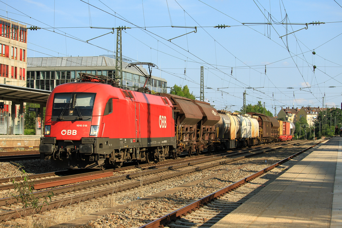 Sehr fotogene Fahrzeuge, wie ich finde.
Die 1016 019 der BB durchfhrt mit einem seeeehr langen Mischer den Mnchener Heimeranplatz in Richtung Laim. Das Foto entstand am frhen Abend des 17.August 2018.