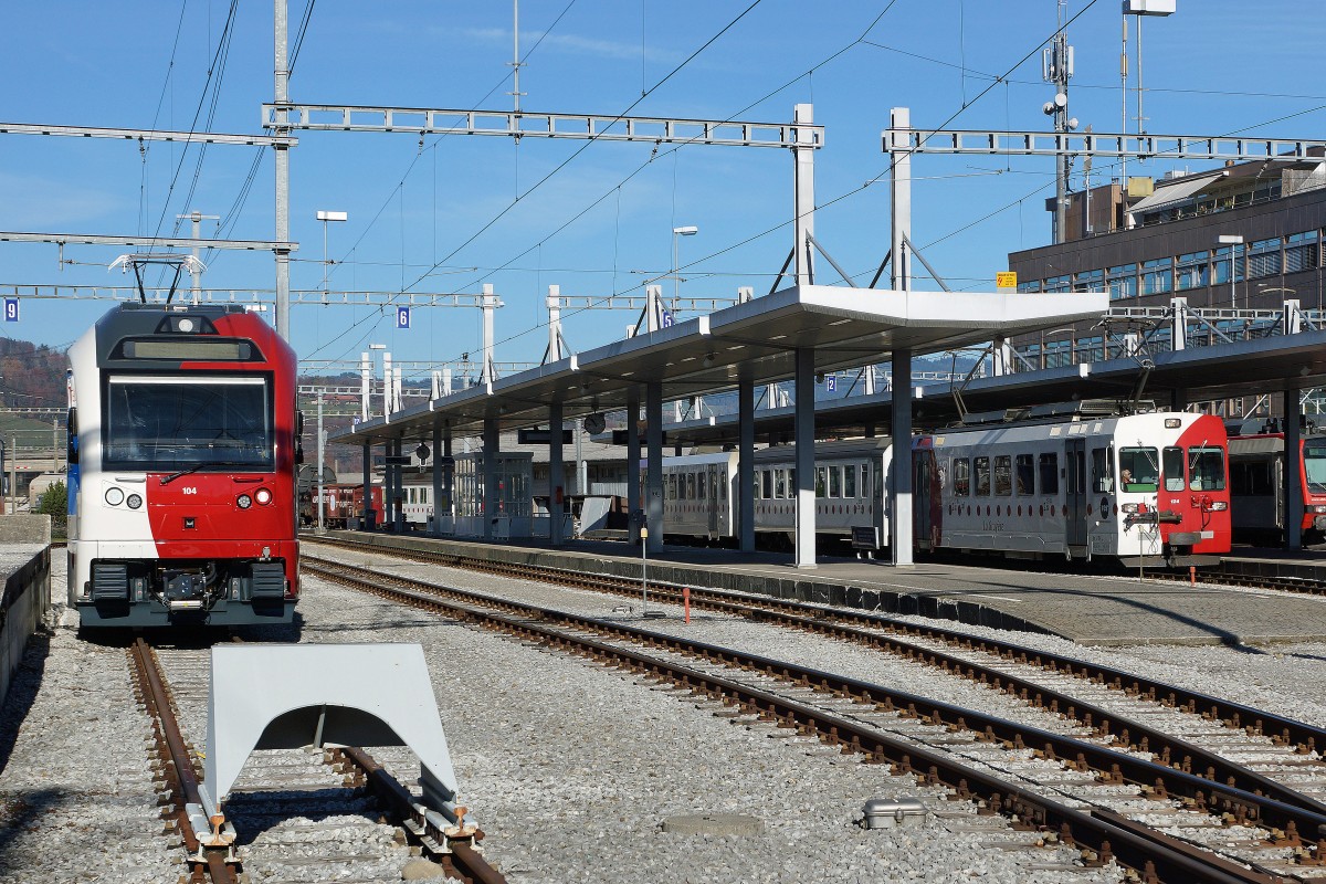 TPF: Der neue dreiteilige Pendelzug von Stadler Rail bestehend aus ABe 2/4 + B + ABe 2/4 und ein dreiteiliger Pendelzug mit dem BDe 4/4 124 (1996) in Bulle am 12. November 2015. Mit den neuen Zgen werden die Be  4/4 151 - 152 und die BDe 4/4 141 - 142 abgelst. Die BDe 4/4 werden zur Zeit auch noch im Rollbockverkehr zwischen Bulle und Broc eingesetzt.
Foto: Walter Ruetsch