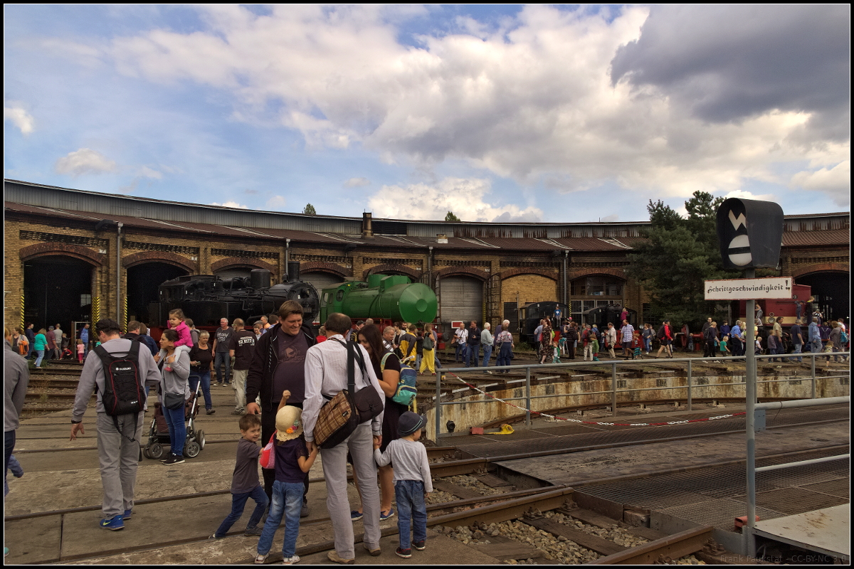 Trotz vermehrter Wolken am Nachmittag kamen zum 15. Berliner Eisenbahnfest am 15.09.2018 im Betriebsbahnhof Berlin-Sch�neweide bei den Berliner Dampflokfreunden e.V. auch viele Familien. Etliche davon sogar mit Kinderwagen, da war das Hinweisschild an der Drehscheibe sogar w�rtlich zu nehmen:  Schrittgeschwindigeit! . Im Hintergrund kann man 74 1230 und die gr�ne FLC 077 erkennen.