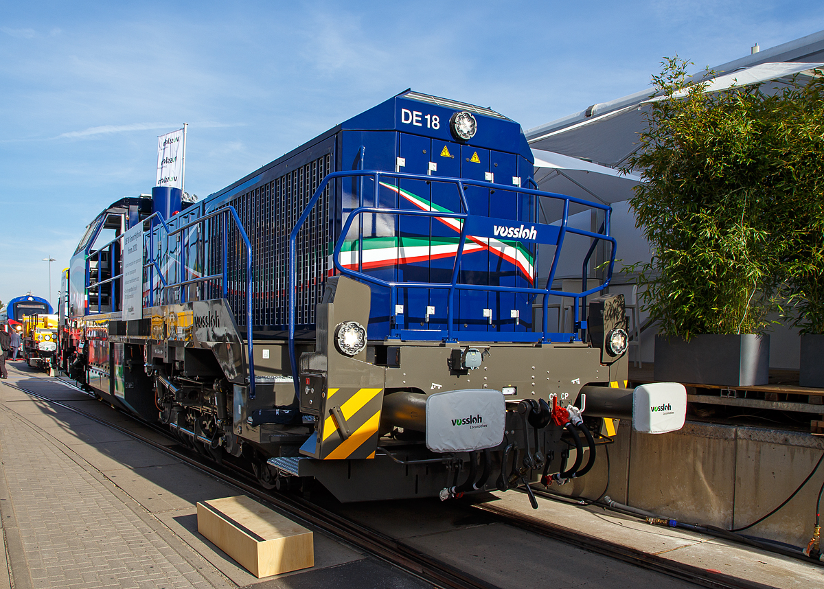 Vossloh Locomotives präsentierte auf der InnoTrans 2018 in Berlin (18.09.2018) seine vierachsige Dieselelektrische Lokomotive DE 18 Smart Hybrid. Hier in Form der für die Eiffage Rail (Frankreich) bestimmte  MF419  (92 87 4185 027-7 F-ERSF), die in Frankreich auch unter der Baureihe BB 79000 geführt wird. Die Lokomotiven wurden für den schweren Rangierdienst und Streckendienst mit hoher Einsatzflexibilität konzipiert.

Diese Lok wurde 2018 von Vossloh in Kiel unter der Fabriknummer 5502354 gebaut, auf der InnoTrans 2018 in Berlin präsentiert und dann an die Eiffage Rail S.n.c. als MF 419 ausgeliefert.

Die DE 18 ist eine relativ leichte Diesellokomotive (80 Tonnen), die überall auf dem französischen Bahnnetz eingesetzt werden kann. Sie ist für Güterzüge bestimmt, kann aber auch für Bahnnetz-Instandhaltungszüge eingesetzt werden (einschließlich auf Hochgeschwindigkeitsstrecken) und sie verfügt über eine besondere Funktionalität für Arbeiten im Tunnel.

Aufgrund des voranschreitenden technischen Fortschritts und den damit verbundenen neuen Möglichkeiten im Bereich der Energiespeicher und Antriebssysteme stehen Eisenbahnverkehrsunternehmen heute stärker denn je vor der Herausforderung, ihre bisherigen Fahrzeuge auf betriebswirtschaftliche Kostenoptimierung hin zu prüfen, und diese gegebenenfalls durch neue umweltfreundlichere, günstigere und leistungsoptimierte Systeme zu ersetzen. Bei der Entscheidung, eine neue Lokomotive für den Rangier- und/oder Streckendienst im Güterverkehr anzuschaffen, stehen neben den vorgesehenen Einsatzarten vor allem auch wirtschaftliche Aspekte und neue, verschärfte Umweltrichtlinien und Gesetze, die den Einsatz in bestimmten Bereichen und Arbeitsumfeldern für Lokomotiven mit hohem Schadstoffausstoß einschränken oder verbieten, im Vordergrund.

Diesen Zeitgeist trifft Vossloh Locomotives mit dem Angebot seiner zur SmartHybrid-Lok der weiterentwickelten DE 18. Bei ihr wird der 1.800 kW starke Dieselmotor um ein bis zu 150 kWh Batteriepaket ergänzt, wodurch Betreiber für Fahrten durch „Zero-Emission“-Bereiche im Tunnel oder während des Hallenbetriebs, je nach Lastprofil, über einen mehr als einstündigen Rangierbetrieb ohne Emissionen verfügen. Der erweiterte Start-Stopp-Support des Dieselmotors führt zu zusätzlichen Schadstoffreduzierungen und bringt effektive Einsparungen bei den Treibstoff und Wartungskosten.

Das Akkusystem mit neuester Lithium-Ionen-Technologie ist ohne komplexe Zusammenschaltung mit dem Dieselmotor im Bauraum des Zusatztanks integriert. Als Plug-In-Lösung wird die Batterie ökologisch sinnvoll über Nacht aus Fremdstromversorgung oder in Bereichen mit optimalem Dieselmotorwirkungsgrad über den Dieselmotor geladen. Je nach Einsatz des Akkus umfasst die Lebenszeit zwischen 3.000 und 6.000 Ladezyklen.

Eingefügt in den hochmodernen Antriebsstrang mit ETCS und Länderzulassungen für Deutschland, Frankreich und Luxemburg soll diese optionale Baugruppe 2019 getestet und 2020 für den kommerziellen Betrieb geliefert werden können. Die französische Akiem hat 44 dieser Dieselelektrischen Lokomotiven bei Vossloh Locomotives gekauft, die letzte soll bis Anfang 2022 geliefert werden. Die Akiem verleast diese an SNCF Réseau. Nach diversen Anpassungsarbeiten werden die Wartungslokomotiven BB 79000 von der SNCF Réseau schrittweise in Betrieb genommen. Die Vossloh-DE 18 werden Arbeiten auf Hochgeschwindigkeitsstrecken (LGV) durchführen und auch der TGV-Notfallversorgung dienen. 

TECHNISCHE DATEN:
Spurweite:  1.435 mm (Normalspur)
Achsformel:  Bo'Bo'
Länge über Puffer : 17.000 mm
Drehzapfenabstand: 7.940 mm
Achsabstand im Drehgestell: 2.400 mm
Raddurchmesser: 1.000 mm (neu) / 920 mm (abgenutzt)
Größte Höhe: 4.310 mm
Größte Breite: 3.080 mm
Höchstgeschwindigkeit: 120 km/h
Dieselmotor: 12 Zylinder-90°-V-Dieselmotor mit Registeraufladung, Ladeluftkühlung und Common-Rail-Einspritzung vom Typ MTU 12V 4000 R 84
Motorhubraum: 57.2 l (Ø 170 mm Bohrung x 210 mm Hub)
Motorabmessungen: 2.670 x 1.696 x 2.001 mm
Motorgewicht: 7.700 kg (trocken)
Abgasvorschriften: EU IIIB
Dieselmotorleistung: 1.800 kW
Dieselmotornenndrehzahl: 1.800 U/min
Traktionsleistung am Rad: 1.440 kW
Anfahrzugkraft: 300 kN
Dauerzugkraft: 230 kN bei 24,2 km/h
Dienstgewicht: 80 t
Kraftstoffvorrat: 4.000 l
Batteriepaket: 150 kWh
Fahrmotoren: 4 Asynchronmotoren
Stromrichter : IGBT
Elektrodynamische Bremsleistung: max. 1.450 kW
Bremse: Druckluftbremse KE-GP-E
Kleinster befahrbarer Bogenradius: 55 m
Zugsicherung: KVB, RPS, DAAT, TVM 430, GSM-R radio,
