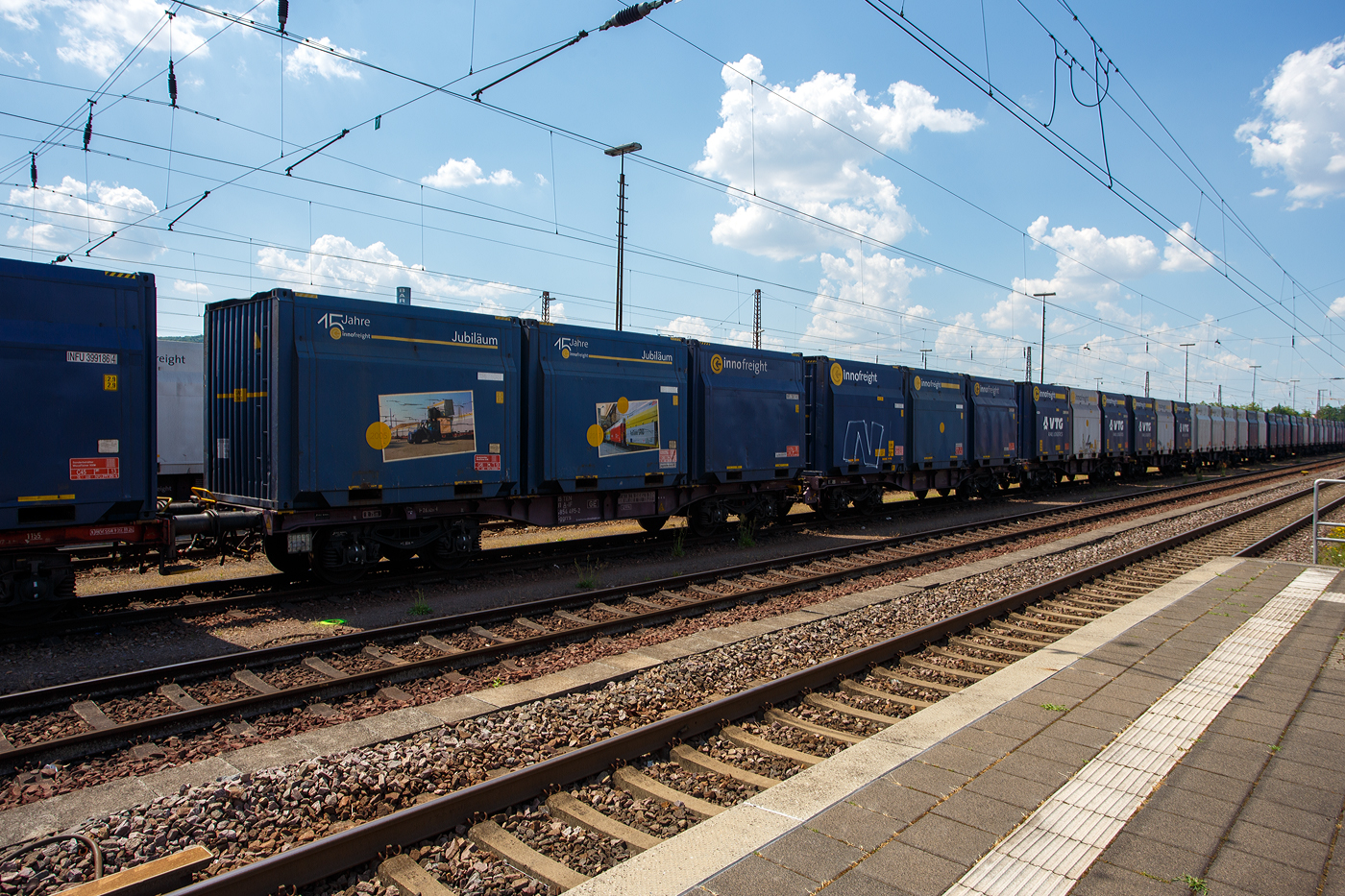 2 x 4-achsiger Flachwagen in Sonderbauart (Doppelwagen) bzw. ein 8-achsiger Containertragwagen, 31 81 4854 495-2 A-IF, der Gattung Sggrrs 80 ft, der �sterreichischen INNOFREIGHT hier als Wagon der Variante D02 - WoodTainer XXM mit sechs aufgesetzten WoodTainer XXM (2 x 3) mit einer L�nge von je 13' (KV Profil C45) vermietet an die DB Cargo AG, am 01 Juli 2025 abgestellt im Zugverband in Dillingen/Saar.

Grunds�tzlich besteht ein InnoWaggon aus zwei kurzgekuppelten Einzelwagen. Leichtbauweise und hohe Belastbarkeit differenzieren diese Waggons dabei klar von anderen und erm�glichen deutlich h�here Zuladung f�r den Transport von unterschiedlichsten G�tern. Der InnoWaggon vereint den Tragwagen und die auswechselbaren Beh�lter zu einem innovativen Konzept, das eine flexible Nutzung verspricht. Der Einsatz der Spezialbeh�lter wird dabei der jeweiligen Branche angepasst, da die Beh�lter je nach Anforderung wie spezifisches Sch�ttgewicht oder Entladestation eingesetzt werden.


TECHNISCHE DATEN des 2x40 ft InnoWaggon:
Gattung: Sggrrs
Gattungskennzahl: 4854
Hersteller: Tatravagonka Poprad (Slowakei), 
Spurweite: 1.435 mm (Normalspur)
Achsenanzahl: 8 pro Doppelwagen (in 4 Drehgestellen)
L�nge �ber Puffer: 26.710 mm 
Breite: 2.878 mm
Drehzapfenabstand: 2 x 8.070 mm
Achsabstand in den Drehgestellen: 1.800 mm
Raddurchmesser: 920 mm (neu)
L�nge Ladefl�che: 2 x 12.370 mm (2 x 40 ft)
H�he der Ladefl�che �ber SOK: 1.155 mm
Eigengewicht: 42.300 kg
Max. Geschwindigkeit: 100 km/h (beladen) / 120 km/h (leer)
Max. Zuladung pro Doppelwagen: 137,7 t (ab Streckenklasse D 3)
Bremse: KE-GP-A (K)
Bremssohle: C 810
Kleinster befahrbarer Gleisbogen: R 75m
Intern. Verwendungsf�higkeit: TEN-GE

TECHNISCH DATEN eines WoodTainer XXM:
L�nge: 13 ft / 3.962 mm
H�he: 2.900 mm
Breite: 2.900 mm
Eigenwicht: 2.150 kg
Max. Zuladung: 33.850 kg
Max. Gesamtgewicht: 36.000 kg
Ladevolumen: 29 m�
KV Profil: C45

Jeder Container besteht aus fixen Seitenw�nden und Stirnw�nden und ist nach oben hin offen. Im beladenen Zustand k�nnen bis zu drei Container gestapelt werden.

Die Positionierung der WoodTainer XXM auf dem Tragwagen erfolgt unter Verwendung von vier Container-Pins je Container.