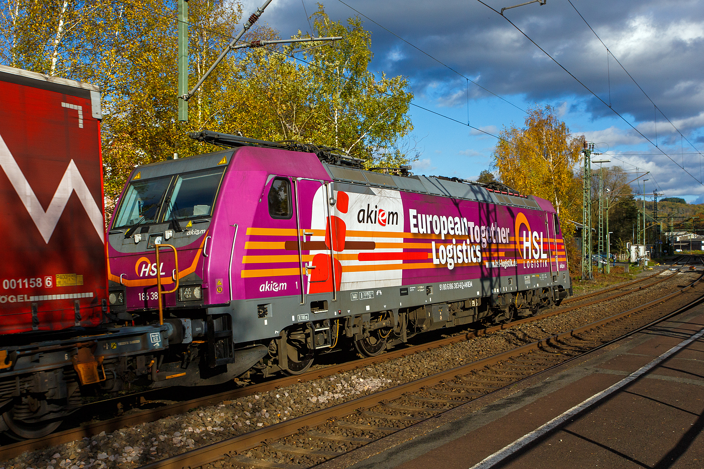 Als Schlussl�ufer, des von der TXL 7193 318 gezogenen KLV-Zugs, am 30 Oktober 2025 durch Scheuerfeld/Sieg in Richtung K�ln, die kalte an die HSL Logistik GmbH (Hamburg) vermietete 186 383-6 (91 80 6186 383-6 D-AKIEM) der AKIEM SAS. 

Die Bombardier TRAXX F140 MS2 wurde 2018 von Bombardier in Kassel unter der Fabriknummer 35415 gebaut. Die f�r 140 km/h zugelassene Multisystemlokomotive hat die Zulassungen/L�nderpaketen f�r Deutschland, �sterreich, die Niederlande und Belgien (D/A/NL/B). 