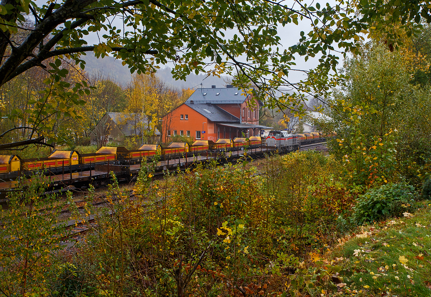 Baustelle Bahnhof Herdorf am 25 Oktober 2025, es sch�ttete ohne Unterlass, dazu noch heftige Windb�en, aber die Arbeiten zur Erneuerung der Weiche 3 und der R�ckbau mit L�ckenschluss f�r die drei aufeinander folgenden Weichen 22, 23 und 24 (Erneuerung Anschluss von Weiche 26 an Gleis 4) haben begonnen. So musste ich doch dem widrigen Wetter an die Strecke. 

Bei dem Wetter haben die Gleisbauarbeiter mein vollstes Mitgef�hl. Da haben es die Lokf�hrer und Baggerfahrer durch den Schutz ihrer Kabine schon besser. 

Hier seht u.a. die 271 022-6 „Charlotte“ (92 80 1271 022-6 D-KAF) eine Vossloh/MaK G 1000 BB der KAF Falkenhahn Bau AG. ex MRCE bzw. ex HGK DH 49, mit einigen Flachwagen. Hinten auf Gleis 1 steht sehr langer Schotterzug (ca. 600 m) an dessen Ende die Vossloh G 12 – 4120 001-7 „Karl August“ (92 80 4120 001-7 D-KAF) befindet. 