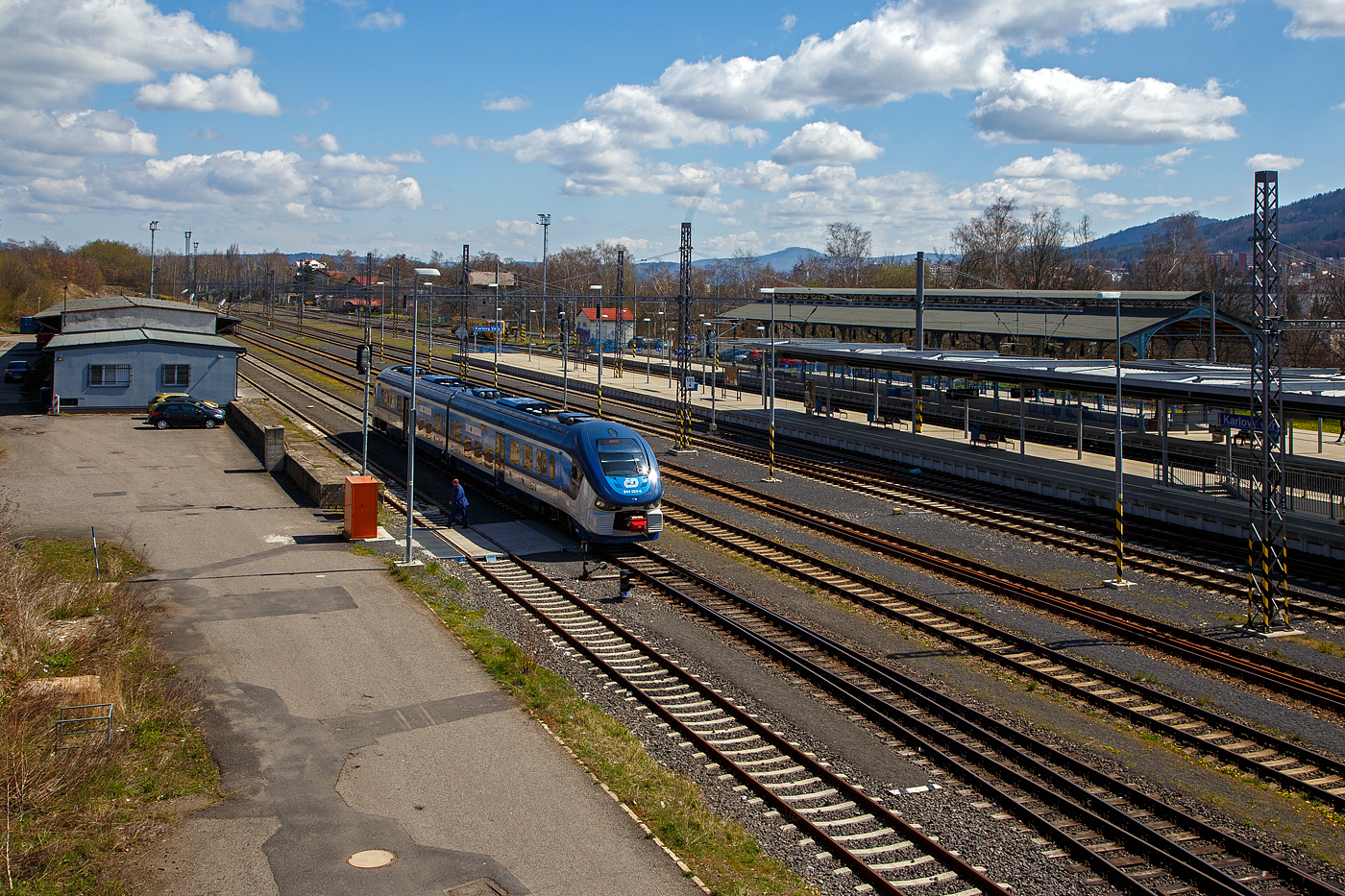 Blick von der Fußgängerbrücke/-überquerung auf den Bahnhof Karlovy Vary (Horním nádražím) / Karlsbad (Oberer Bahnhof), hier am 19.04.2023.

Vorne steht der ČD „RegioShark“ 844 024-0 (CZ-ČD 95 54 5 844 024-0), hinten rechts die denkmalgeschützte Bahnsteigüberdachung vom Kopfgleis 1.