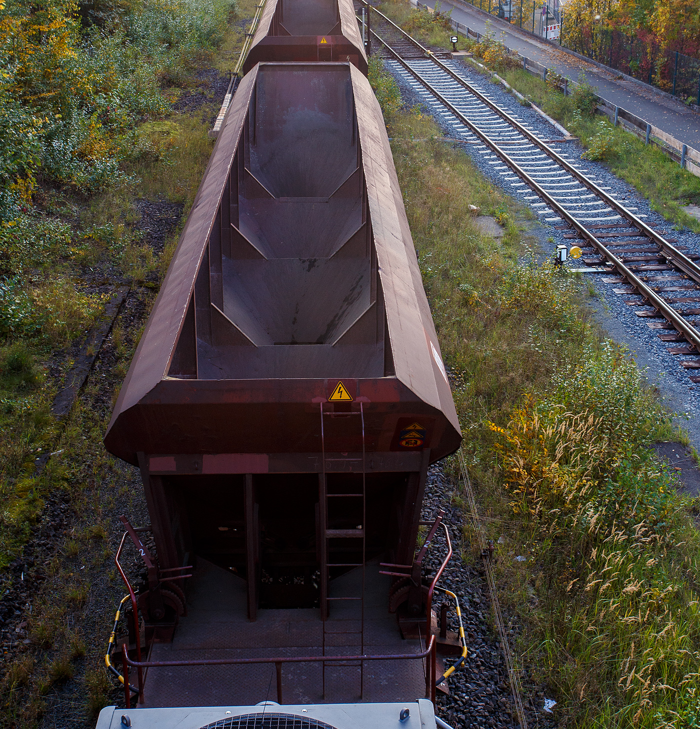 Blick von oben auf den, nun leeren, vierachsigen offenen Drehgestell-Schüttgutwagen mit dosierbarer Schwerkraftentladung, 31 80 6940 387 D-DB, Gattung Facs 124 (ex DR Gattung Eads-y), der DB Cargo AG, steht 12 Oktober 2025, eingereiht in einen Schotterzug hier direkt hinter der Lok, im Bahnhof Herdorf. Gut sieht man hier die vier Kammern/Trichter. 