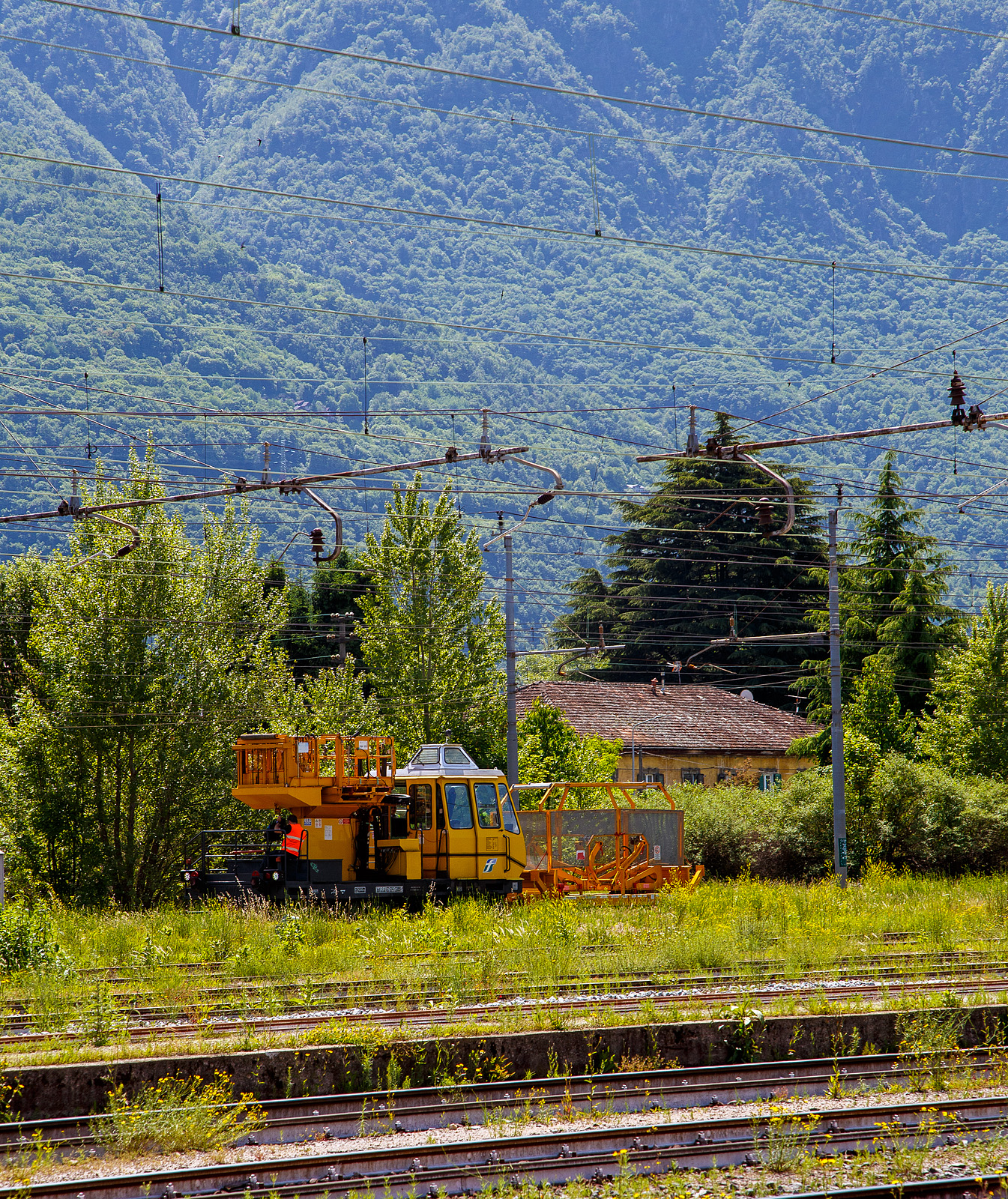 Das Oberleitungsinstandhaltungs-Fahrzeug (Autoscala Pesante) S45 26??  IT-RFI 161291-5 der RFI - Rete Ferroviaria Italiana rangiert am 26 Mai 2023, mit einem vorgestellten zweiachsigen Oberleitungsinstandhaltungs-Wagen mit zwei Haspeln bzw. Trommelbock-Wagen (Svolgibobine Carro recuperatore), beim Bahnhof Domodossola.