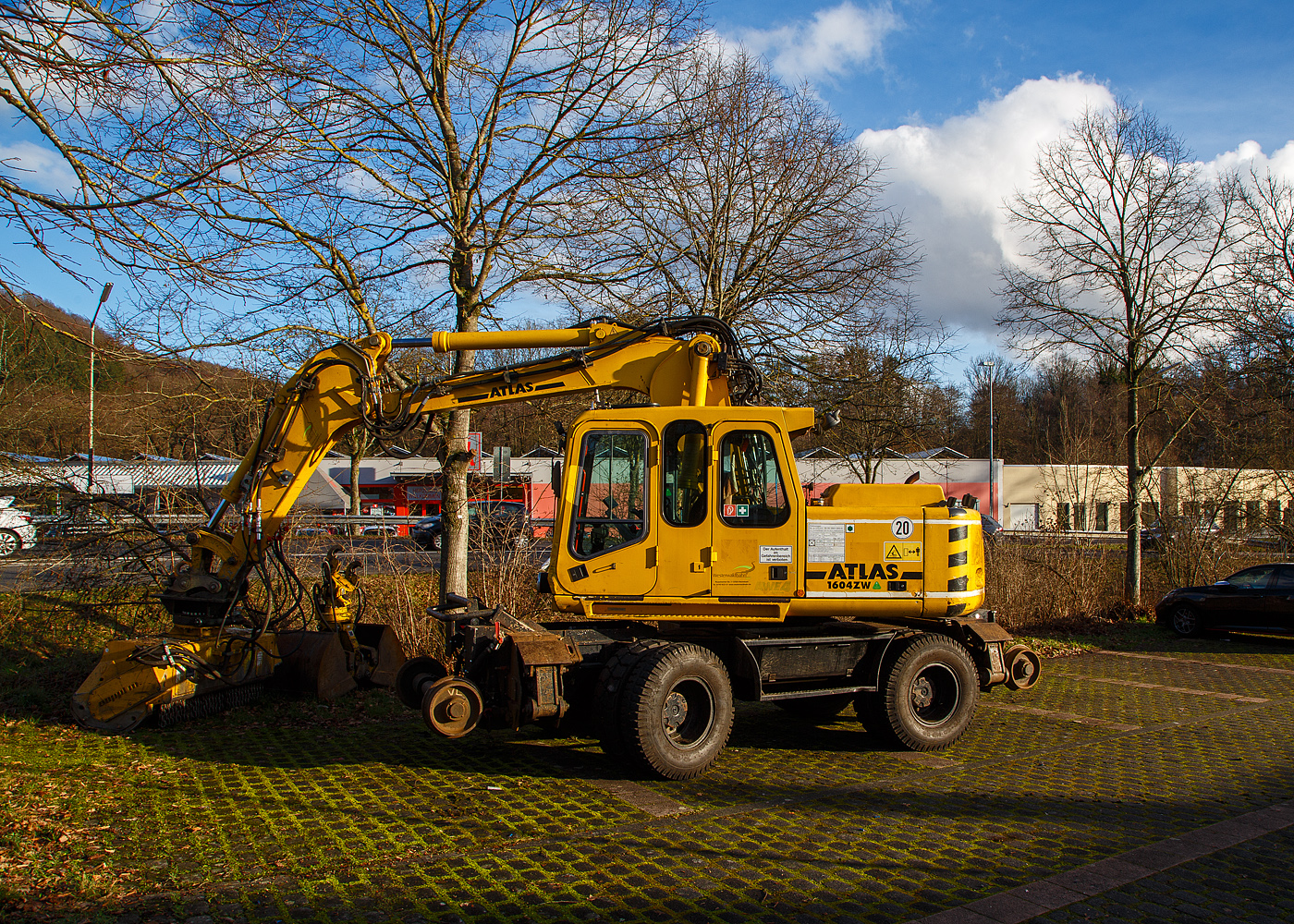 Der ATLAS-TEREX Zweiwegebagger 1604 ZW-WB mit Abstützpratzen, Kleinwagen Nr. D-WEBA 98 80 9901 683-9, der Westerwaldbahn des Kreises Altenkirchen GmbH ist am 07.02.2022, mit einem angebauten SEPPI Baggermulcher BMS 150 der HeringBau, in Betzdorf-Alsdorf auf einem Parkplatz neben Bahnstrecke Betzdorf–Daaden (Daadetalbahn) angestellt.

Der Bagger wurde 2005 ATLAS-TEREX GmbH in Delmenhorst unter der Fabriknummer 168Z301630 gebaut.

TECHNISCHE DATEN des Baggers:
Spurweite: 1.435 mm
Achsabstand: 5.475 mm (Schiene) / 2.550 mm (Straße)
Eigengewicht: 22,2 t
Zul. Gesamtgewicht: 23.000 kg
Motorbauart: wassergekühlter 4-Takt 4-Zylinder Diesel-Reihenmotoren mit Turboaufladung und Ladeluftkühlung
Motortyp: Deutz BF 4M 2012 C
Motorhubraum: 4,04 Liter (101mm / 126 mm Bohrung/Hub)
Motorleistung: 93 kW (127 PS) bei 2.500 U/min
Höchstgeschwindigkeit (Hg): 20 km/h (in Kreuzungen und Weichen 10 km/h)
Bremse: Dir.-Dbr. und Eisenbahnwagenbremsanlage
Zul. Anhängelast: 120 t
Zur Mitfahrt zugel. Personenzahl: 1 (und Fahrer)
Antrieb auf Schiene: Über Reibantrieb der Straßenreifen

Der angebaute Mulcher:
Der SEPPI BMS 150 ist ein leistungsvoller Forstmulcher. Dieser SEPPI Baggermulcher BMS mulcht (zerkleinert Holz) Stubben und Stämme bis zu 30 cm Durchmesser. Die Arbeitsbreite bei diesem BMS 150 beträgt 150 cm, das Gewicht beträgt 1.400 kg. Hersteller ist die SEPPI M. AG in Kaltern (Südtirol) – Italien.