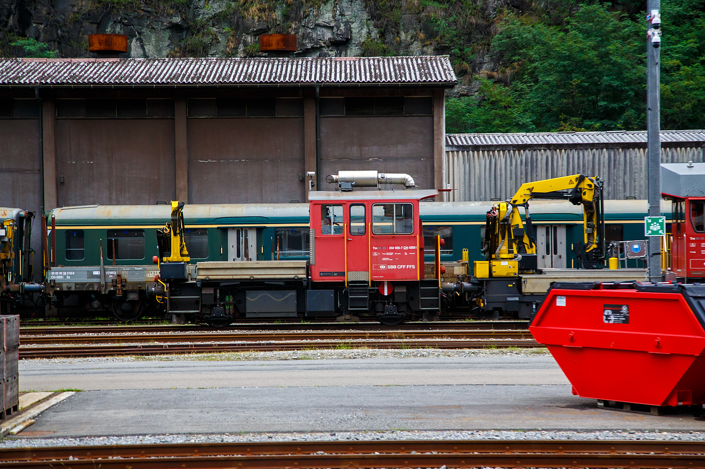 Der Bautraktor bzw. das Baudienstfahrzeug SBB Tm 232 025-7 (Tm 98 85 5 232 025-7 CH SBBI) der SBB Infrastruktur, ex SBB Tm III 9562 (Tm III Baudienst), steht am 02 August 2025 in Airolo. Aufnahme aus einem RE heraus.

Der Tm 232 025-7 wurde 1986 von RACO Saurer und als Tm III 9562 an die SBB geliefert, 2005 erfolgte die Modernisierung (Retrofit und Neumotorisierung) durch Stadler  Winterthur  AG  (Winpro  AG)  und  Windhoff  Bahn- und Anlagentechnik GmbH und die Umzeichnung in SBB Tm 232 025-7.

Der Baudiensttraktor Tm III ist ein bei der Schweizerischen Bundesbahn zahlreich vorhandenes und aufgrund seiner vielfältigen Einsatzmöglichkeiten beliebtes Arbeitsfahrzeug. Die Traktoren sind nur etwas in die Jahre gekommen. Das Beschaffungsprogramm lief zwischen 1976 – 1988 und umfasste insgesamt 103 Fahrzeuge, hiervon waren 90 mit Ladekran und 13 mit Hebebühne ausgerüstet. Die Fahrzeuge weisen zwar alle noch einen guten Erhaltungszustand auf, genügen aber hinsichtlich der Leistungsfähigkeit nicht mehr den Anforderungen des modernen Eisenbahnbetriebes. Die Gründe hierfür sind, die Schwache Motorisierung, die geringe Höchstgeschwindigkeit und Zugkraft, zudem befassen sie kein Zugsicherungssystem.

Das Konsortium bestehend aus der Stadler Winterthur AG  (Winpro AG)  und der  Windhoff  Bahn- und Anlagentechnik GmbH in Rheine (D) haben für die SBB insgesamt 52 dieser 2-achsigen Traktionsfahrzeuge für die Baudienste  (Traktoren) des Typs Tm 232 modernisiert. Im Februar 2006 wurde das letzte Fahrzeug übergeben. Das Retrofitprogramm umfasste die Steigerung der Fahrzeugleistung (Höchstgeschwindigkeit von 60 auf 80 km/h / Zugkraft um ca. 80-100 %) und die umweltgerechte Motorisierung/EURO III, den Einbau des Zugssicherungssystems und die Erneuerung des Krans mit erhöhter Leistungsfähigkeit. Das Auftragsvolumen lag bei rund 26 Mio. CHF, eine Neuanschaffung hätte das Doppelte gekostet. 

Die revidierten Fahrzeuge dienen der aktuellen Flottenpolitik der Divison Infrastruktur, da diese Art von Fahrzeugen einen wesentlichen Bestandteil aller Traktoren der Baudienste der SBB ausmacht. Die 103 Basis-Fahrzeuge des Typs Tm III (Baudienst) beschaffte die SBB in den Jahren 1976-1988. Stadler Winterthur und Windhoff haben zwischen Februar 2004 und Februar 2006 insgesamt 52 dieser Fahrzeuge im Rhythmus von 2 Wochen nach jeweils rund 10 Wochen Revisionszeit pro Fahrzeug abliefern. Die SBB setzt diese revidierten Fahrzeuge landesweit ein, unter anderem in Regionen mit Tunnelbautätigkeiten. Mit dem Einbau des neuen Motors können die Verordnungen betreffend Emissionswerte nach EURO III dank integriertem Partikelfilter eingehalten werden. Die technischen Anforderungen an das Retrofitprogramm beinhalteten folgende Punkte. Die Höchstgeschwindigkeit konnte auf 80km/h in Eigenfahrt und 100 km/h geschleppt erhöht werden. Ebenfalls wurde ein Kran (Palfinger 1,4 t) mit erhöhter Leistungsfähigkeit und ein Zugssicherungssystem Integra eingebaut.

In dem Focus der Arbeiten wurde als erstes das Antriebsaggregat gerückt. Der vorhandene Saurer-Dieselmotor (mit 165 kW Leistung) wurde durch einen modernen EURO III-Motor ersetzt. Der neue Motor ist ein Iveco Cursor 8 (7.790 cm³ /7,79 Liter Hubraum) ein Reihen-Sechszylinder-4-Takt-Dieselmotor mit Turbolader und variabler Geometrie (VGT), mit einer Leistung von 259 kW (352 PS) Leistung. Er hat ein maximales Drehmoment von 1.280 Nm. Das vorhandene Voith-Getriebe wird komplett revidiert und konnte aufgrund seiner Baukastenstruktur um eine Wandlerstufe erweitert werden, so dass der Traktor jetzt mit einem Voith-Getriebe L2r4sV2 Getriebe ausgerüstet ist.

Das Fahrzeug und Kran verfügen jeweils auch über eine neue Funksteuerung.

TECHNISCHE DATEN (Tm 232.0):
Spurweite: 1.435 mm (Normalspur)
Achsformel: B' (2/2)
Länge über Puffer:  8.740 mm
Breite: 3.150 mm
Höhe: 4.450 mm
Achsabstand: 4.800 mm	
Treibdurchmesser: 950 mm (neu) / 870 mm (abgenutzt)
Dienstgewicht: 25 t
Motor: 4-Takt-Dieselmotor mit Turbolader und variabler Geometrie (VGT) vom Typ Iveco Cursor 8
Motorhubraum: 7.790 cm³ (7,79 Liter)
Motornennleistung: 259 kW (352 PS) bei 2.000 U/min
Maximales Motordrehmoment: 1.280 Nm
Getriebe: Voith L2r4sV2
Kraftübertragung: hydrodynamisch, 2-Gang mit Retader
Tankvolumen: 550 Liter (Diesel)
Höchstgeschwindigkeit: 80 km/h bei Eigenfahrt / 100 km/h geschleppt
Kleinster befahrbarer Kurvenradius: R = 35 m
Anhängelast:  280 t bei ‰, 62 t bei 12 ‰
Kran: Palfinger mit 1,4 t Hubkraft
