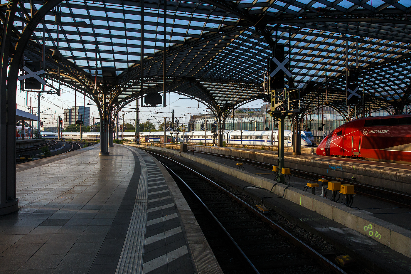 Der blaugestreifte ICE 3neo – Velaro MS, Tz 8029 „Europa/Europe“ (93 80 5408 029-7 D-DB etc.) der DB Fernverkehr AG, verlässt am 18 Juni 2025, als ICE 222 von Frankfurt (Main) Hbf nach Amsterdam Centraal, den Hauptbahnhof Köln. Rechts steht der Eurostar PBKA 4321, als Eurostar EST 9414 von Dortmund Hbf via Köln und Brüssel nach Paris Nord. 

Der ICE 3neo Tz 8029 wurde 2024 von SIEMENS gebaut, er hat die Zulassungen für Deutschland, Belgien und die Niederlande. Der Zug wurde am 23 September 2024 in Belgiens Hauptstadt Brüssel, das ja auch Hauptsitz der Europäischen Union ist, auf den Namen „Europa/Europe“ getauft. Gleichdrauf am selben Tag folgte der erster Fahrgasteinsatz als Sonderzug ICE 13411 Brüssel–Berlin, zur InnoTrans 2024.

Der ICE 3neo ist das neue Flaggschiff der DB Zugflotte, von diesen hat die DB Fernverkehr AG 90 achtteilige Einheiten bestellt (z.Z. sind 38 geliefert). Die Züge ergänzen seit Dezember 2022 die 300-km/h-Flotte und lösten ab Juni 2024 die Züge der Baureihe 406 auf den „ICE International“-Linien nach Belgien und in die Niederlande ab. 

Die ICE 3neo– Velaro MS basieren auf der bewährten Velaro-Plattform und sind eine Weiterentwicklung der Baureihe 407. Die neuen, für 320 km ausgelegten Züge werden als ICE 3neo vermarktet. Die ICE der Baureihe 408 sollen komfortabler werden, acht Fahrradstellplätze pro Garnitur aufweisen, 16 Plätze für Familien sowie 5 Plätze für Kleinkinder bieten. Ein Novum sind frequenzdurchlässige Scheiben für einen stabilen Mobilfunkempfang.

Die besonderen Merkmale und Neuerungen des ICE 3neo:
Besonders die Fahrgäste werden von den Neuerungen und dem Komfort profitieren. Das bereits im ICE 4 bewährte Beleuchtungssystem mit wechselnden Farbtönen wird auch im ICE 3neo installiert. Neu gestaltete Gepäckregale bieten mehr Stauraum als in gegenwärtigen ICE-Zügen. Rollstuhlfahrer werden den neuen Hublift für einen leichteren Zustieg zu schätzen wissen. Radfahrer wird es freuen, dass in jedem ICE 3neo acht Fahrradstellplätze zur Verfügung stehen. Für ein zügiges Aus- und Einsteigen sorgen zusätzliche Türen. In beiden Wagenklassen befinden sich Tablet-Halter und Steckdosen an allen Sitzplätzen. Mobilfunkdurchlässige Scheiben ermöglichen einen stabileren Empfang von Sprache und Daten. Eine konsequente Modulbauweise ermöglicht einen schnellen und einfachen Austausch defekter Bauteile im ICE 3neo. Das schließt auch die Kaffee- und Spülmaschinen im Bordbistro ein. Seit dem 17. Zug sind die ICE 3neo mit dem neuen ICE-Innendesign ausgestattet: Die komplett neu entwickelten Sitze sind als persönlicher Rückzugsort konzipiert, bieten bessere Verstellmöglichkeiten und somit noch mehr Komfort. Eine harmonische Formgebung, moderne Materialien wie Holzdekor und Bezüge aus hochwertigem Stoffgewebe bestimmen das neue Erscheinungsbild. Für die Sitzbezüge werden warme Grautöne in der 1. Klasse, Blautöne in der 2. Klasse und Burgundy-Rot im Bordrestaurant verwendet. 

Allgemein:
Alle Züge bestehen aus acht Wagen und werden gegenüber den bauähnlichen Zügen der Baureihe 407 mit zwei Außentüren je Seite (408.6 und 408.8) mehr, sowie einer exklusiv für Rollstuhlfahrer vorgesehenen Tür (408.3) ausgestattet. Weitere Änderungen gegenüber der Baureihe 407 sind unter anderem:
•	8 Fahrradstellplätze im Endwagen 2. Klasse
•	geänderte Hublifte
•	Farbige Akzentbeleuchtung
•	mehr Gepäckregale
•	Mobilfunktransparente Scheiben
•	WC mit neuem Design und berührungslosen Desinfektions- und Seifenspendern
•	ETCS-Fahrzeuggerät Siemens Trainguard 200 statt Hitachi Rail STS
•	optimierte Galley

Aufbau der Triebzüge:
Wagennummer (Gattung) | Beschreibung           |    Sitzplätze
29/39 (Apmzf 408.0) 	       Endwagen 1. Klasse 	45 (1. Klasse)
28/38 (Apmz 408.1)            Mittelwagen 1. Klasse 	54 (1. Klasse)
26/36 (BRmz 408.2) 	       Bordrestaurant 	23 (2. Klasse) / 16 Restaurant
25/35 (Bpmbsz 408.3)        2. Kl.- und Servicewagen 38 (2. Klasse) / 2 Rollstuhlplätze
24/34 (Bpmz 408.8) 	       Mittelwagen 2. Klasse 	 76 (2. Klasse)
23/33 (Bpmz 408.7) 	       Mittelwagen 2. Klasse 	 76 (2. Klasse)
22/32 (Bpmz 408.6) 	       Mittelwagen 2. Klasse 	 76 (2. Klasse)
21/31 (Bpmdzf 408.5) 	       2. Kl. End- und Fahrradwagen 51 (2. Klasse) / 8 Fahrradplätze

TECHNISCHE DATEN 3neo (Baureihe 408):
Hersteller:	Siemens Mobility
Baujahre: 	ab 2021
Baureihe: 408
Zulassungen für: Deutschland, Belgien und die Niederlande.
Spurweite:	1.435 mm (Normalspur)
Achsfolge: 	Bo’Bo’+2’2’+Bo’Bo’+2’2’+2’2’+Bo’Bo’+2’2’+Bo’Bo’
Anzahl der Achsen / davon angetrieben: 32 / 16
Länge über Kupplung: 200.720 mm (200,72 m)
Länge Wagenkasten:  EW 25,7 m / MW 24,2 m
Höhe (über SOK): 4.343 mm 
Breite: 2.924 mm
Fußbodenhöhe: 1.240 mm (über SOK)
Drehzapfenabstand: 17.375 mm
Achsabstand im Drehgestell: 2.500 mm
Drehgestell-Typ: SF 500
Treib- und Laufraddurchmesser: 920 mm (neu) /830 mm (abgenutzt)
Leergewicht: 460 t
Dienstgewicht: 493 t
Dauerleistung: 16 x 500 kW = 8.000 kW bei AC / 4.200 kW bei DC
Anfahrzugkraft: 300 kN 
Höchstgeschwindigkeit: 320 km/h, 280 km/h in Belgien (Wechselspannung), 200 km/h (3 kV =), 160 km/h (1,5 kV =)
Stromsysteme: 15 kV, 16,7 Hz ~ / 25 kV, 50 Hz ~ / 1,5 kV = / 3 kV =
Stromabnehmer: 2 x AC 15 kV (16,7 Hz), 1.950 mm Wippenbreite / 2 x AC 25 kV (50 Hz), 1.600 mm Wippenbreite / 2 x DC 1,5 oder 3 kV, 1.950 mm Wippenbreite. Alle Pantographen und deren Pneumatik- und Steuerungsbaugruppen sind vollständige Neuentwicklungen von Siemens Mobility.
Sitzplätze: 439, davon 99 (1. Klasse), 340 (2. Klasse), zudem 16 im Restaurant
Rollstuhlstellplätze: 2
Fahrradstellplätze: 8