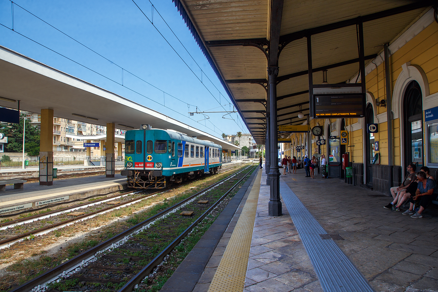 Der Dieseltriebwagen ALn 668 3032 (95 83 4668 332-8 I-Ti) der Trenitalia (100-prozentige Tochtergesellschaft der FS) steht am 19 Juli 2022, als Regionalzug als R 12946 nach Augusta, im Bahnhof Syrakus (Stazione di Siracusa). 

Der Dieseltriebwagen (Verbrennungstriebwagen) wurde 1980 von der Officine Meccaniche Calabresi O.ME.CA S.p.A. in Reggio Calabria gebaut und an die FS - Ferrovie dello Stato Italiane (Italienische Staatseisenbahnen) geliefert. Mit der Aufteilung in einzelne Betriebsgesellschaften der FS im Jahr 2000 kam der VT zur heutigen Tochtergesellschaft Trenitalia.

Die O.ME.CA. (deutsch Kalabrische Mechanische Werkstätten) war ein Hersteller von Schienenfahrzeugen mit Sitz in der Stadt Reggio Calabria, später gehörte sie zur AnsaldoBreda S.p.A., im Laufe der Zeit führte der Auftragsrückgang zu einer Verkleinerung der gesamten AnsaldoBreda-Gruppe und seit Februar 2015 gehört sie zur Hitachi Rail Italy S.p.A.. Die Stadt Reggio Calabria liegt an der Südspitze der italienischen Apenninhalbinsel (Stiefelspitze) und somit an der Ostseite der Straße von Messina gegenüber von Messina (Sizilien).
