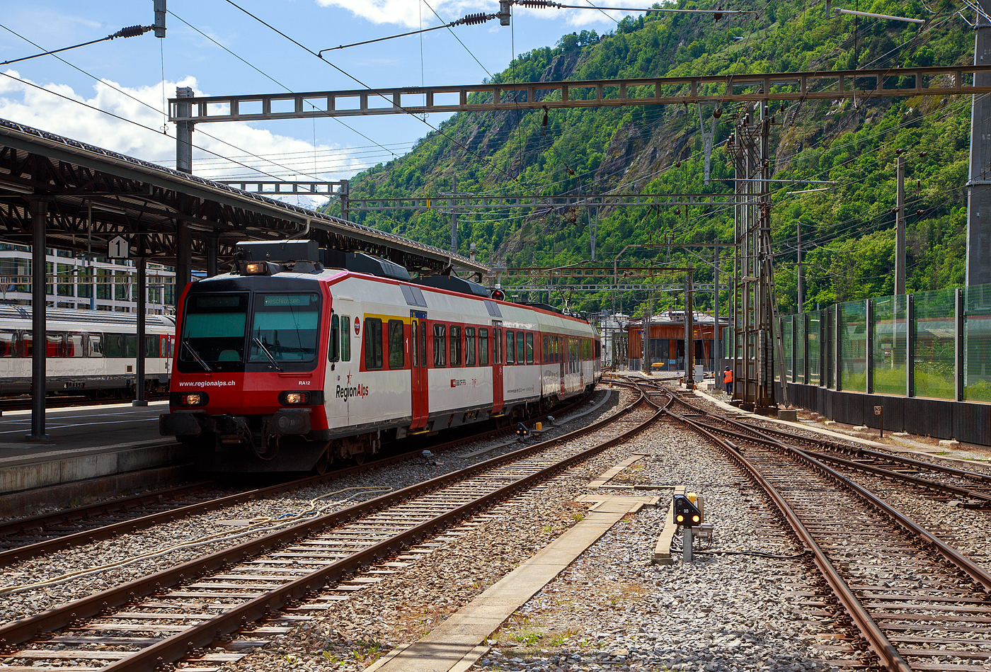 Der dreiteilige NPZ Domino RA12 der RegionAlps (ex SBB RBDe 4/4) erreicht am 25.05.2023 als Regio (St-Gingolph–St-Maurice –Martigny–Sion–Brig), Steuerwagen voraus, seinen Zielbahnhof Brig.

Der NPZ Domino besteht aus:
1./2. Klasse Steuerwagen ABt NPZ DO RA 50 85 39-43 948-1 CH-RA
Modernen 2.Klasse INOVA-Zwischenwagen mit Niederfluranteil B NPZ DO RA 50 85 29-43 407-0 CH-RA
und dem 
Triebwagen RBDe 560 DO RA 94 85 7 560 412-9 CH-RA, ex SBB RBDe 560 010-1 (Umbau 2009).

Die Regionalps (RA) ist ein Eisenbahnverkehrsunternehmen im Kanton Wallis, mit Sitz in Martigny hat. Eigentümer derim Jahr 2003 gegründete Gesellschaft  sind die Schweizerischen Bundesbahnen (SBB) mit 70 %, die Transports de Martigny et Régions (TMR) mit 18 % und der Kanton Wallis mit 12 %. Die RA betreibt den Regionalverkehr vor allem im Rhonetal zwischen dem Ostufer des Genfersees und Brig. Inzwischen gehören Regionalps 16 dreiteilige NPZ Domino (Trieb-, Zwischen- und Steuerwagen ex SBB) und 4 RABe 525 NINA (ex TMR).

Als RBDe 4/4 wurden die Triebwagen der Schweizerischen Bundesbahnen (SBB) bezeichnet, die ab 1984 für die als Neuer Pendelzug (NPZ) bezeichneten Regionalzugskompositionen mit den dazugehörenden Steuerwagen angeschafft wurden. Sie tragen seit 1990 die Baureihenbezeichnung RBDe 560. Aus Kostengründen wurde damals auf die Beschaffung neuer Zwischenwagen verzichtet, verwendet werden stattdessen umgebaute Einheitswagen (EW I und EW II).

Die meisten von 1987 bis 1996 gebauten Fahrzeuge RBDe 560, 561 und 568 durchliefen 2008 bis 2013 ein Komplett-Modernisierungsprogramm. Aus aufgearbeiteten Trieb- und Steuerwagen sowie neu beschafften Zwischenwagen entstanden Regionalverkehrs-Kompositionen mit der Bezeichnung «Domino». Die Triebwagen werden dabei einheitlich als RBDe 560 (94 85 7 560 XXX-X) bezeichnet. Sie können in Vielfachsteuerung verkehren.

TECHNISCHE DATEN (Komposition RBDe 560, B und ABt) :
Spurweite:  1.435 mm (Normalspur)
Achsformel:  Bo’Bo’ +2´2´+2´2´
Länge über Puffer:  25.000 mm / 24.700 mm / 25.000 mm
Drehzapfenabstand: 17.600 mm / 18.900 mm /17.600 mm
Achsabstand im Drehgestell: 2.700 mm (ZW 2.500 mm)
Treib- und Laufraddurchmesser: 950 mm
Höhe:  3.750 mm
Breite:  2.860 mm
Dienstgewicht:  72 t (Triebwagen) + 36 t (ZW) + 38 t (Steuerwagen)
Höchstgeschwindigkeit: 140 km/h
Dauerleistung:  1.650 kW (2.250 PS)
Anfahrzugkraft:  182 kN
Dauerzugkraft: 78 kN
Anzahl Fahrmotoren: 4
Stromsystem:  Wechselstrom 15 kV 16,7 Hz
Sitzplätze: 54 (TW) / 60 (ZW) / 12+60 (SW) = 186 (12 in der 1. Klasse)
Ladegewicht: 0,3 t (Triebwagen)
Kupplungstyp: Schraubenkupplung