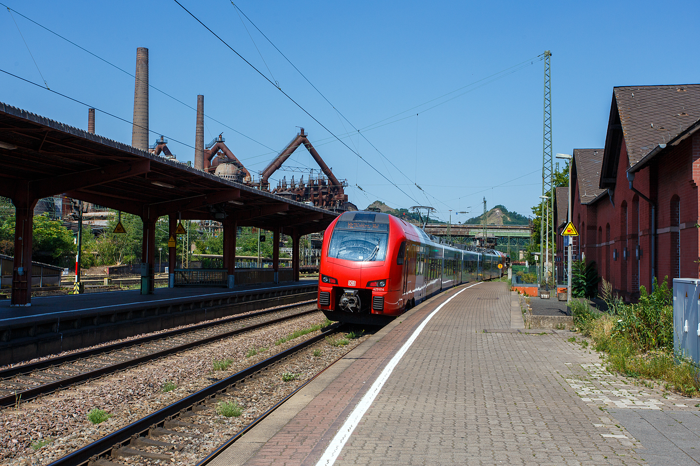 Der fünfteilige SÜWEX Stadler FLIRT 3 – 429 114 / 429 614, als RE 1  Südwest-Express  (Kaiserslautern – Trier – Koblenz), verlässt am 01 Juli 2025 den Bahnhof Völklingen und fährt weiter in Richtung Dillingen. Ich finde das neue Farbdesign der SÜWEX (Südwest-Express), mit den nun roten Triebwagenköpfen, ist für mich gelungener als das alte Farbdesign.

Im Hintergrund das Ziel unserer Reise an diesem Tag, das Weltkulturerbe Völklinger Hütte. Die Völklinger Hütte ist weltweit das einzige Eisenwerk aus der Blütezeit der Industrialisierung, das vollständig erhalten ist. Seit 1994 zählt es zum UNESCO-Weltkulturerbe.