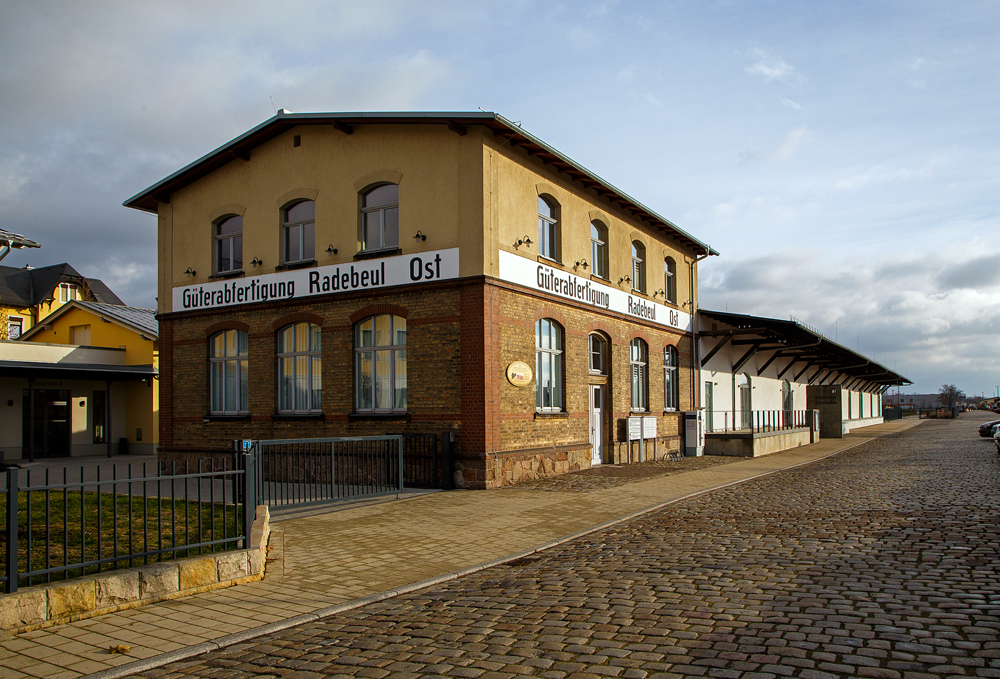 Der Gterboden des Bahnhofs Radebeul Ost am 07.12.2022.
Der historische Gterboden des Bahnhofs Radebeul Ost ist Teil des Bahnhofsensembles des Bahnhofs Radebeul Ost der schsischen Stadt Radebeul. Der denkmalgeschtzte Gterboden ist ein Einzeldenkmal der Sachgesamtheit der schmalspurigen Lnitzgrundbahn. Auf der Straenseite zu den Gleisen hin befindet sich die Auenaufstellung insbesondere der Ausstellung historischer schsischer Schmalspurfahrzeuge im Eigentum des Verkehrsmuseums Dresden, die seit Januar 2005 in die Obhut des SSB Schmalspurbahnmuseums Radebeul bergeben wurden, sowie weiterer Fahrzeuge der Traditionsbahn Radebeul (TRR) und der Schsischen Dampfeisenbahngesellschaft (SDG). Das von der Denkmalpflege dem Standort Radebeul Ost zugeordnete rollende Gut findet sich in der Liste der Radebeuler Kulturdenkmale der Lnitzgrundbahn, ebenso wie die weiteren zum Schmalspurbahnhof gehrenden Immobilien wie Heizhaus, Kohleschttung oder Wasserkran.
